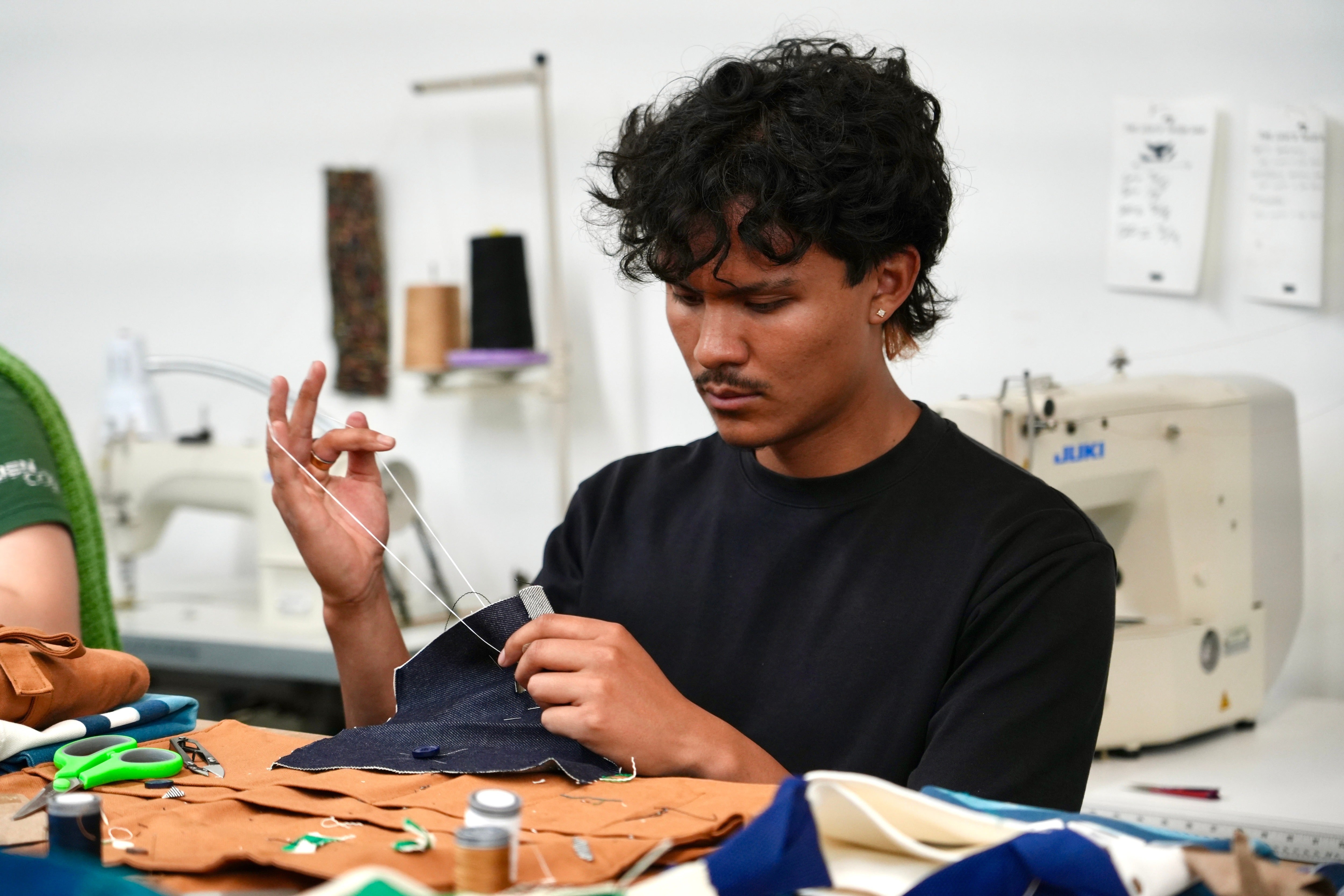 Jesse Sanchez practices sewing during a clothing repair workshop at a Levi's retail store in downtown San Francisco in July 2026 (AP Photo/Terry Chea)