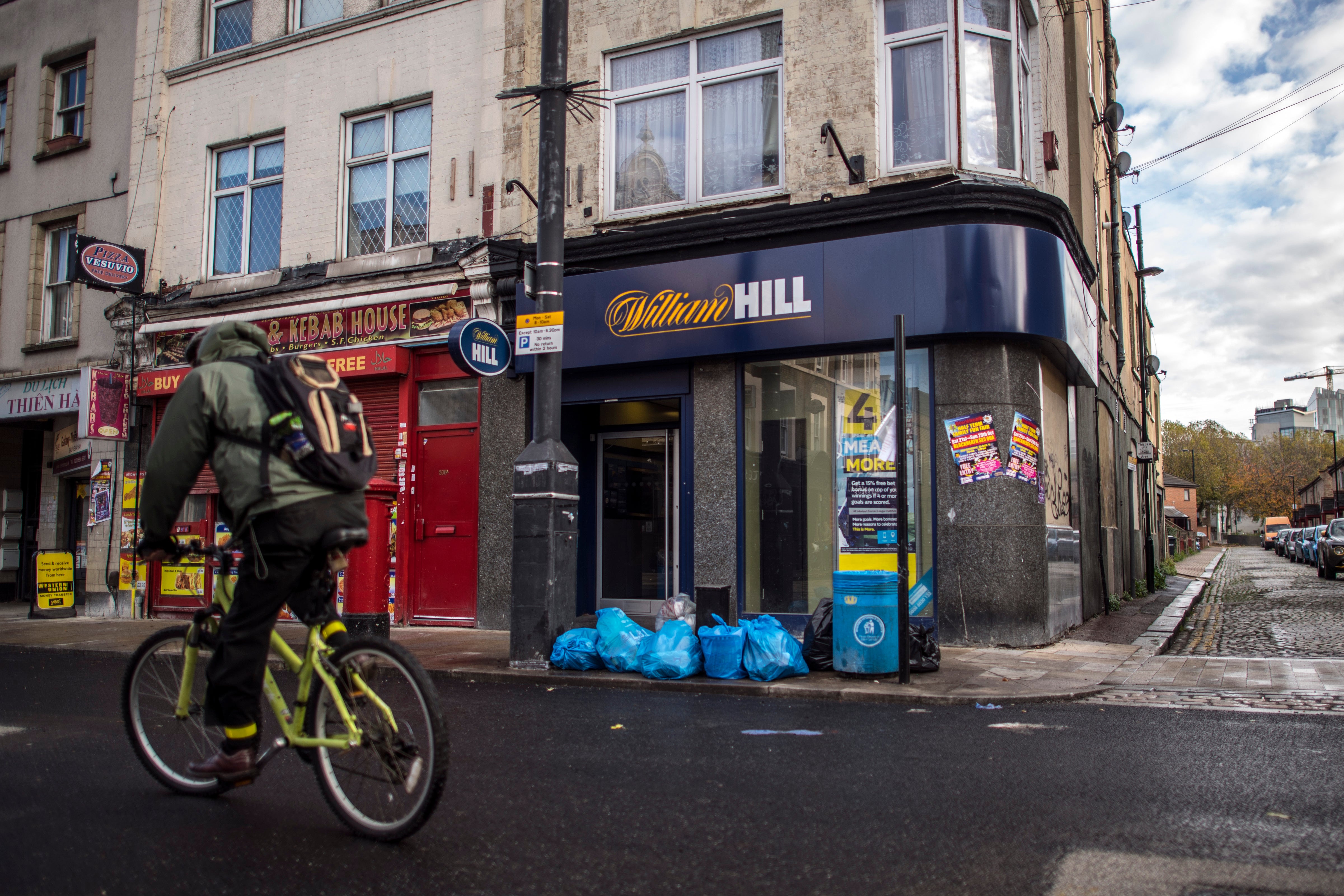 A man cycles past a William Hill bookmakers on Deptford High Street, London. Councils are set to have greater powers to reject new applications for bookmakers