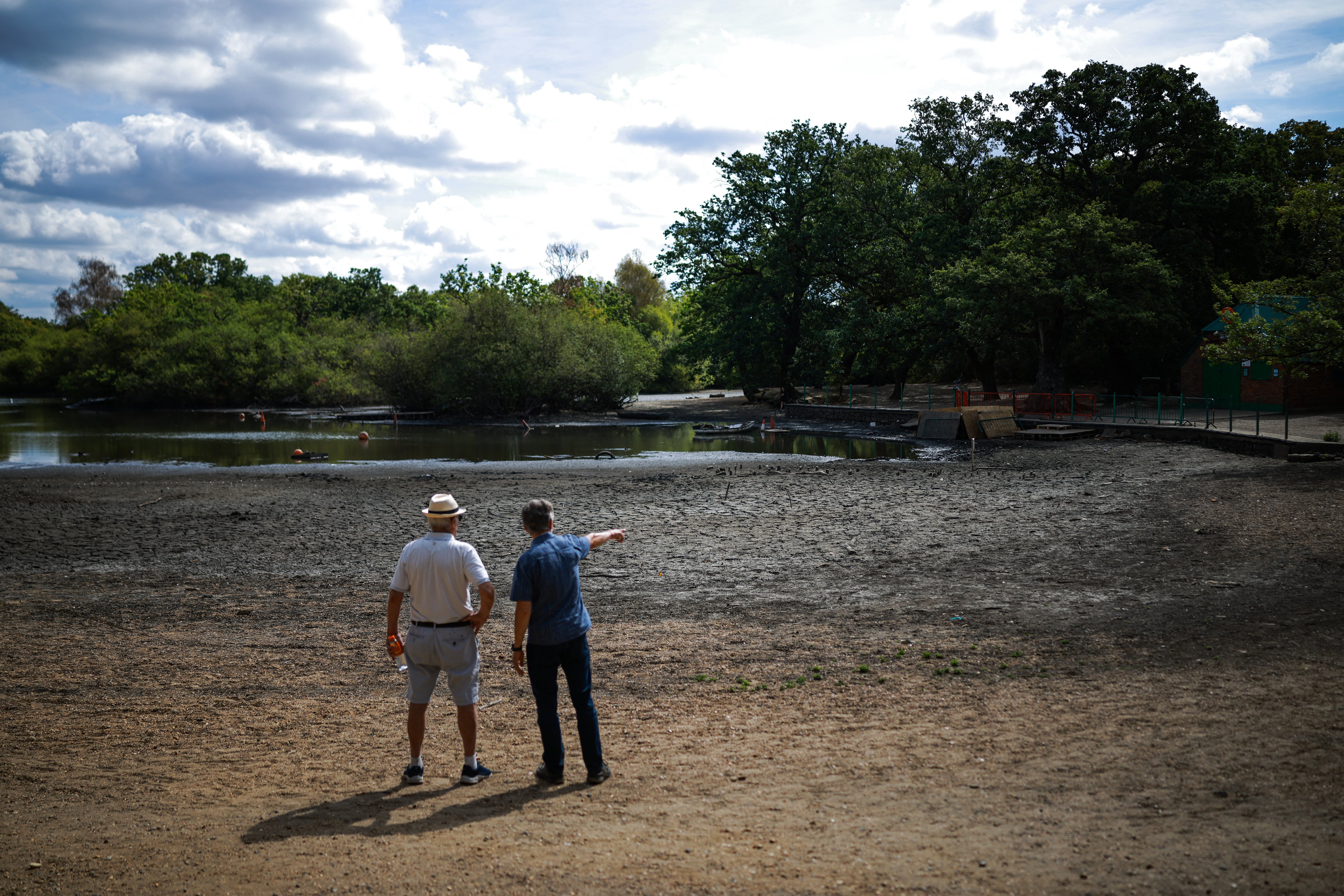 People look out over the dried and cracked bed of the depleted Hollow Pond and Leyton flats near Wanstead, east London