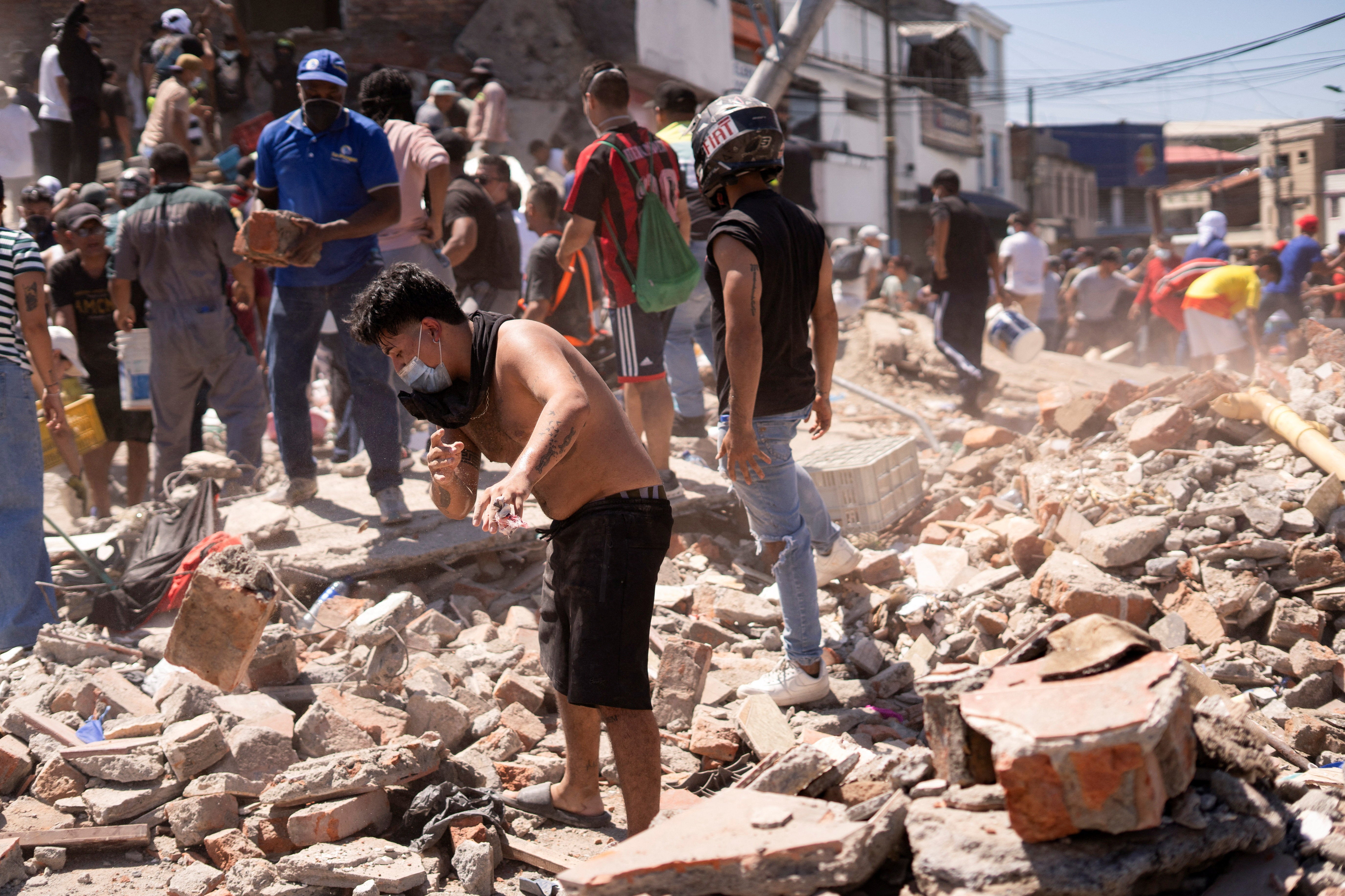 Residents dig through the debris of a collapsed building after an earthquake in Cali on Monday (Reuters)