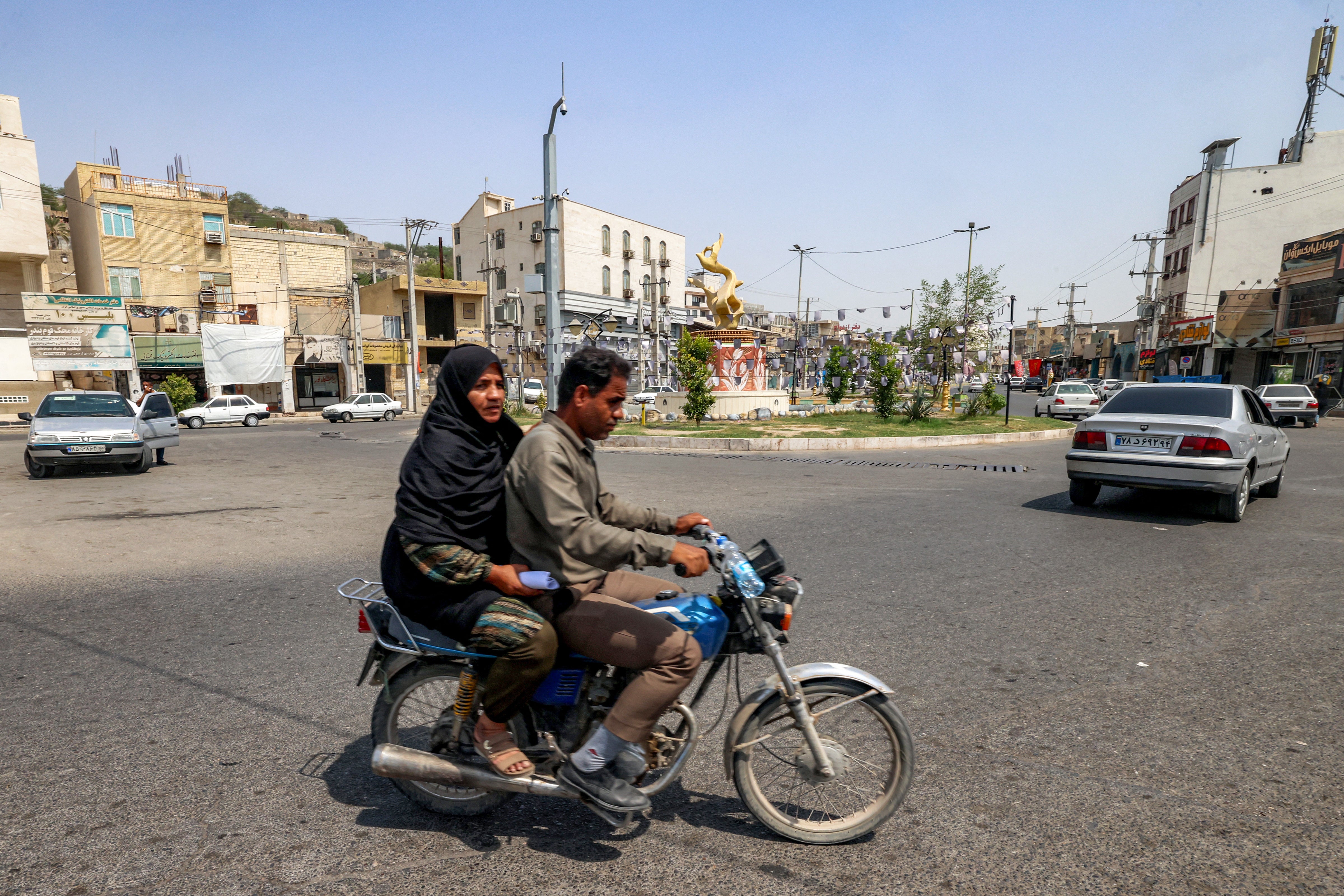 A woman rides behind a man on a motorcycle in Minab in Iran's southern Hormozgan province on August 10