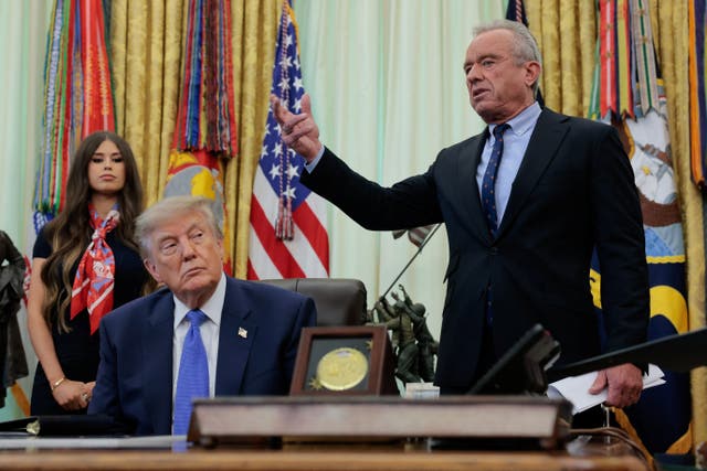 President Donald Trump sitting at the Resolute Desk with Secretary of Health and Human Services Robert F. Kennedy Jr.