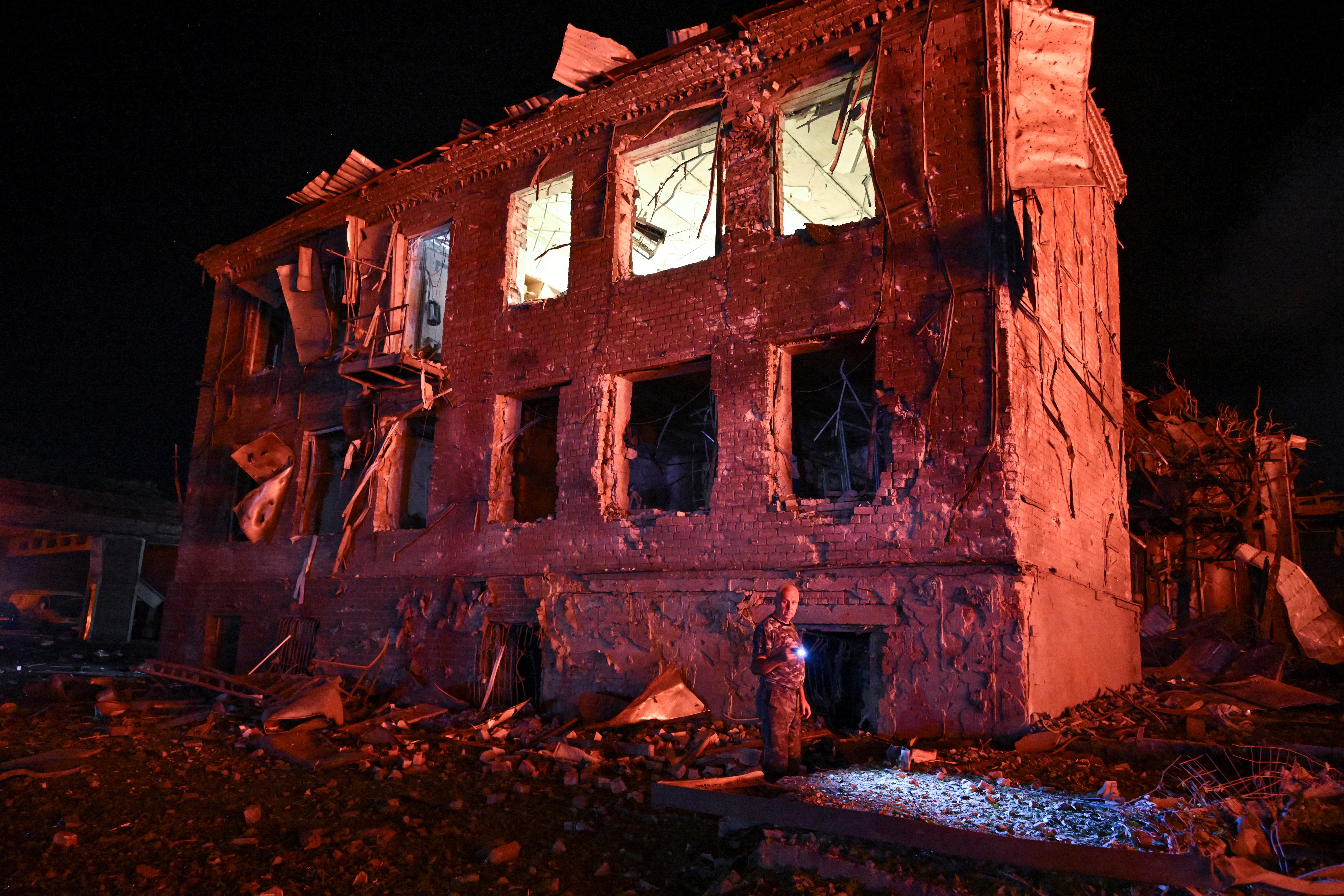A resident stands next to a building damaged by an overnight Russian missile strike, amid Russia's attack on Ukraine, in Zaporizhzhia