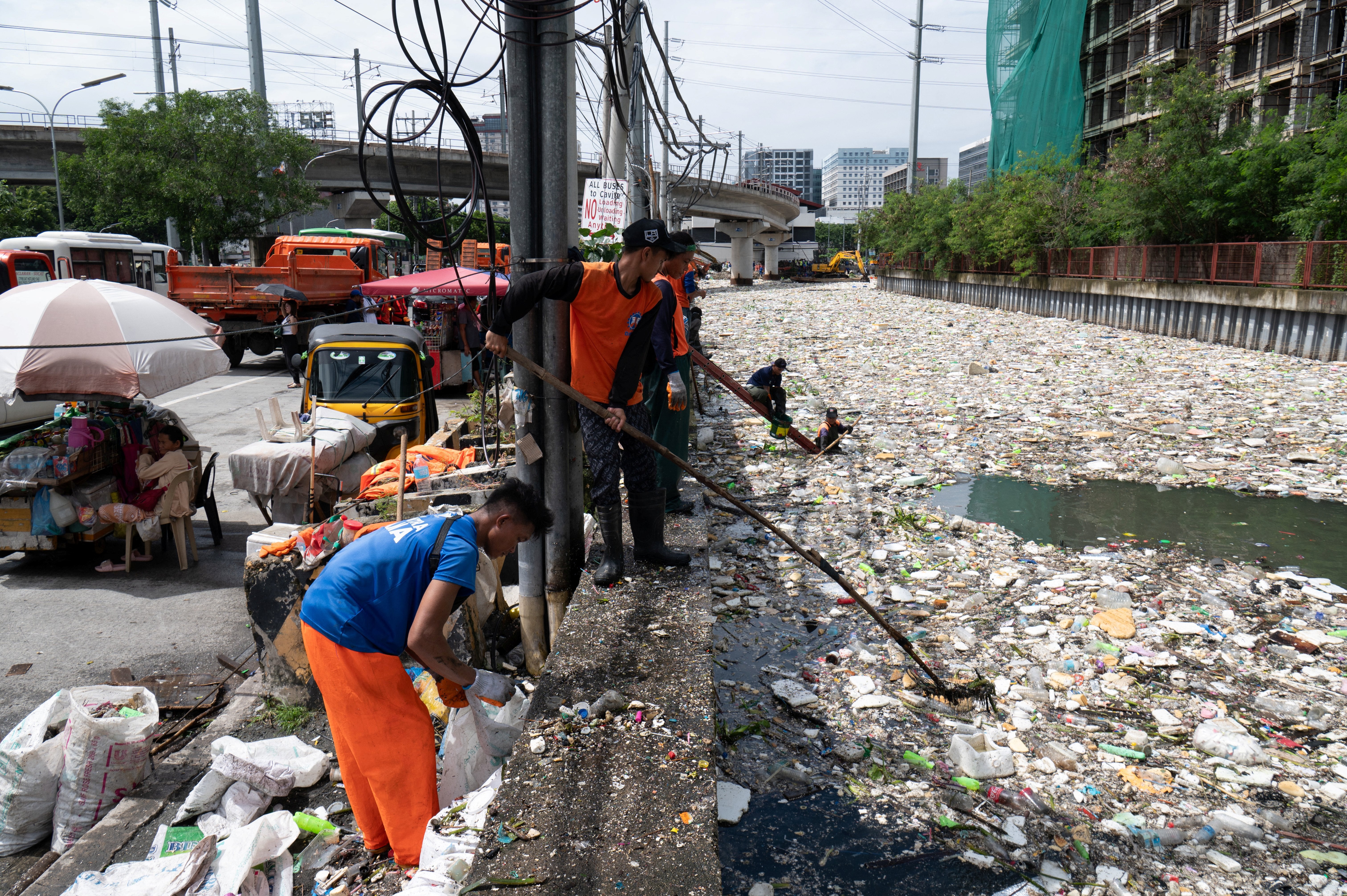 Workers scoop rubbish from a river near a shopping complex in Paranaque City, suburban Manila