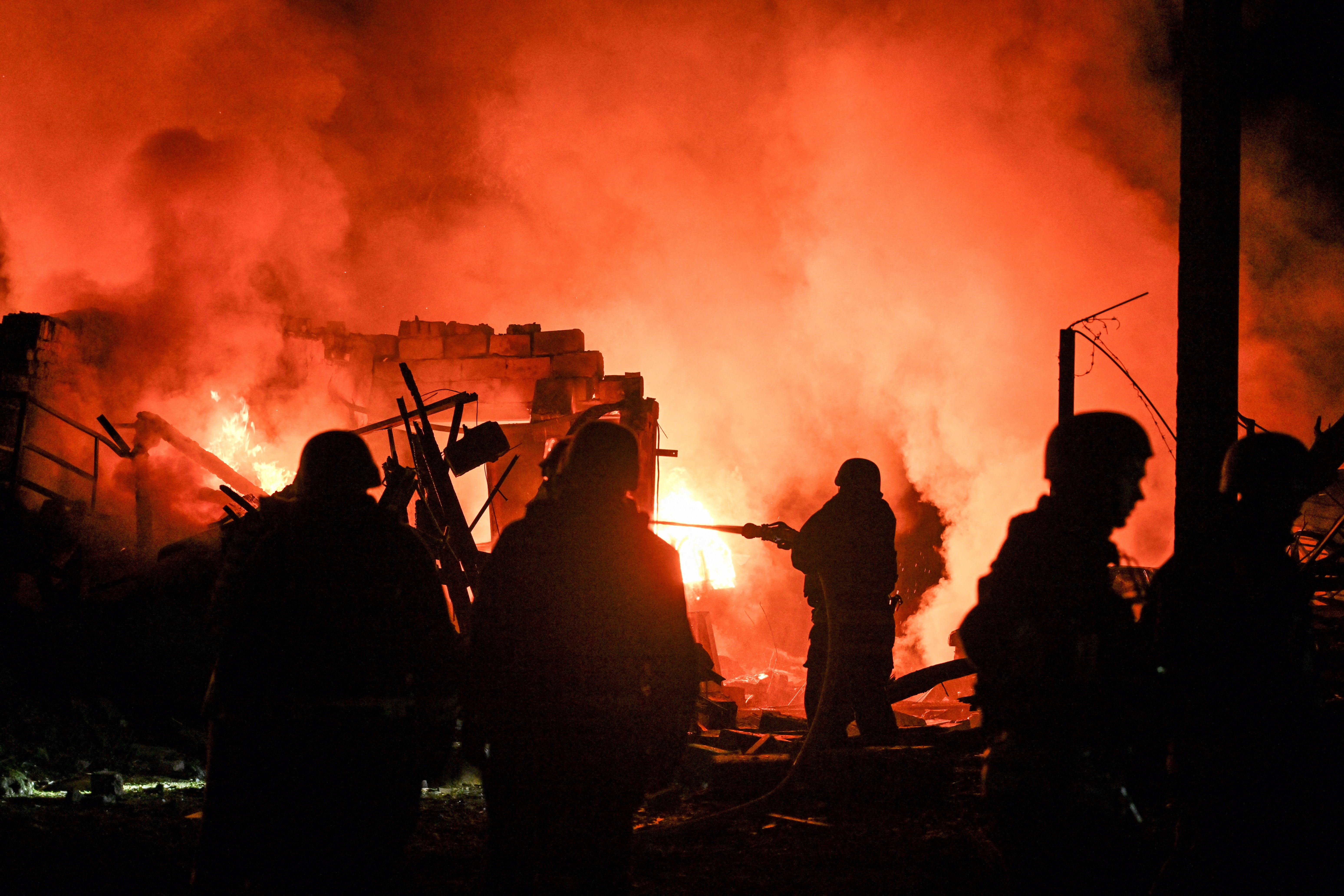 Firefighters work at the site of a car garages of residents which were hit by an overnight Russian missile strike