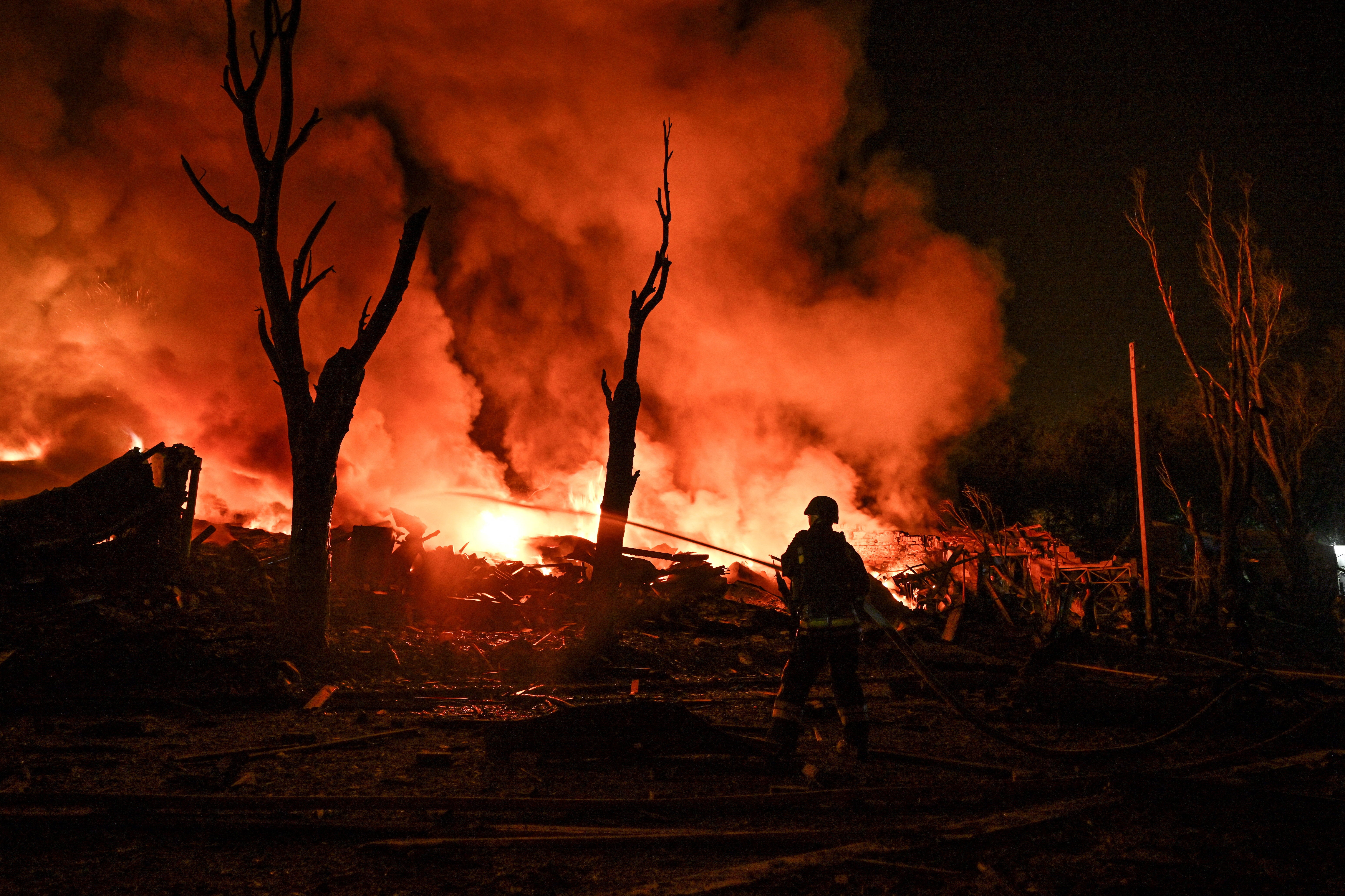 A firefighter works at the site of a car garages of residents which were hit by an overnight Russian missile strike