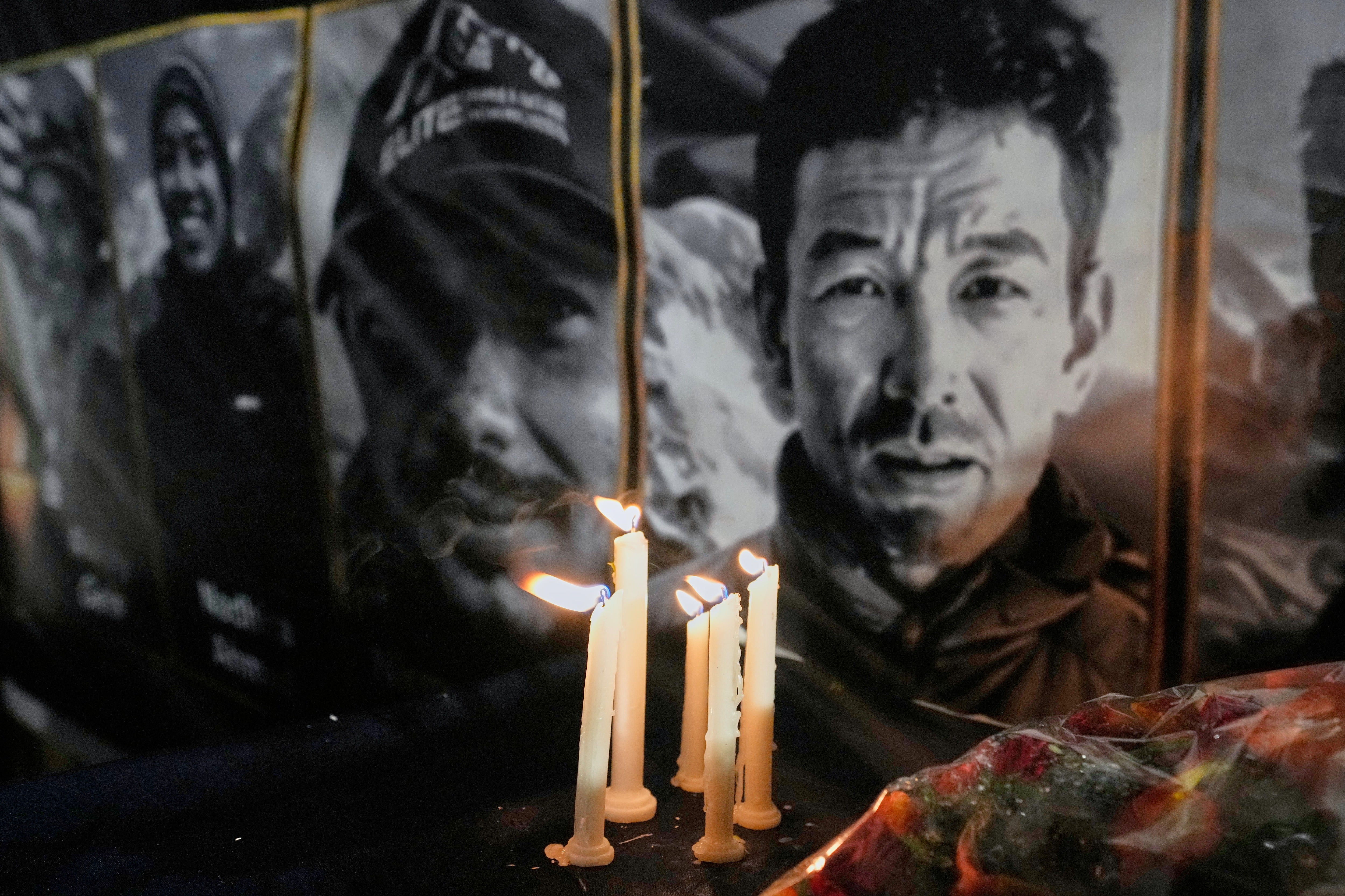 Candles burn next to pictures of climbers who lost their lives on Broad Peak