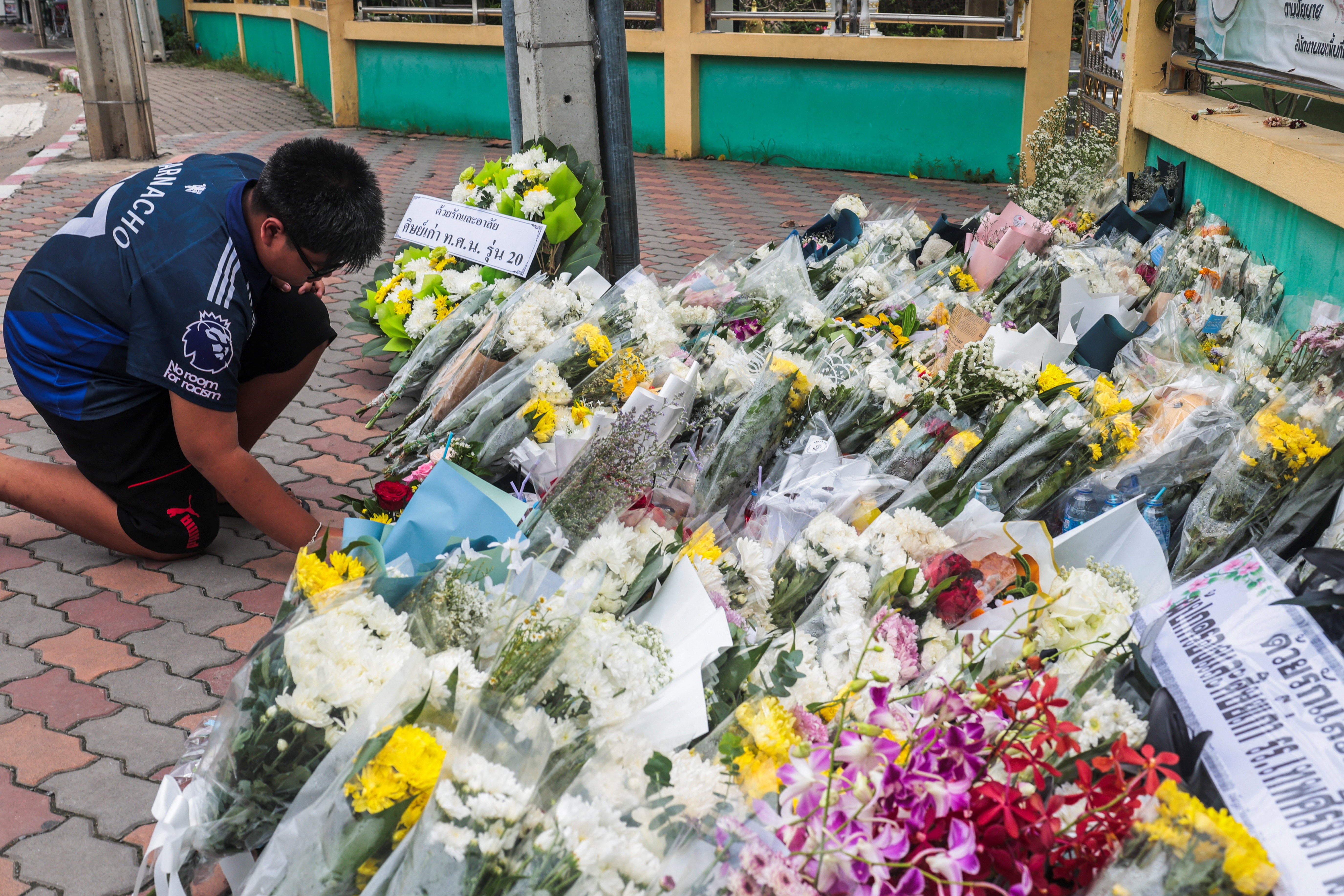 A student leaves flowers following a deadly shooting at the Debsirin Nonthaburi School on the outskirts of Bangkok