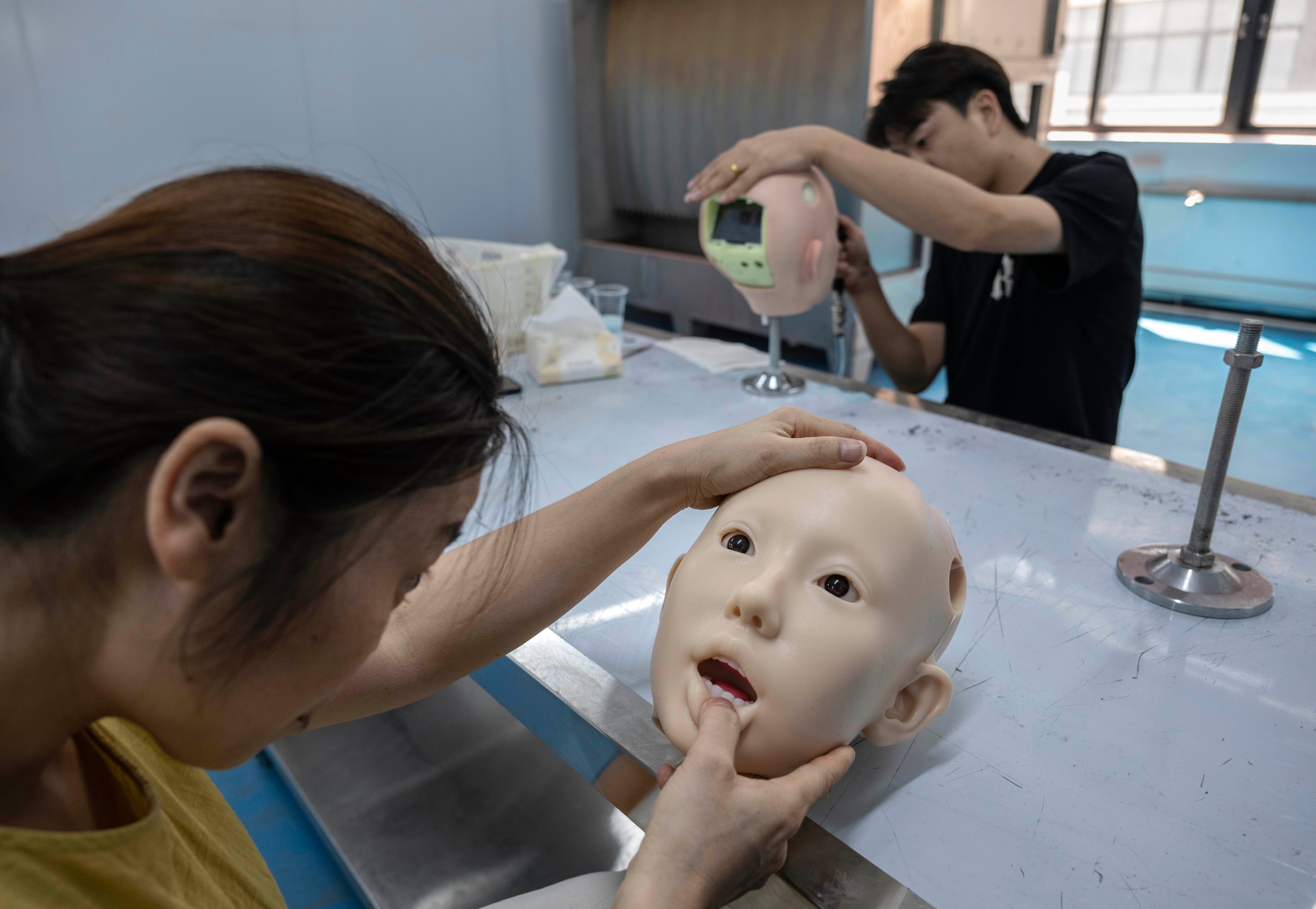 Staff members work with robotic heads for silicone sex dolls at a factory for WM Dolls (Getty)