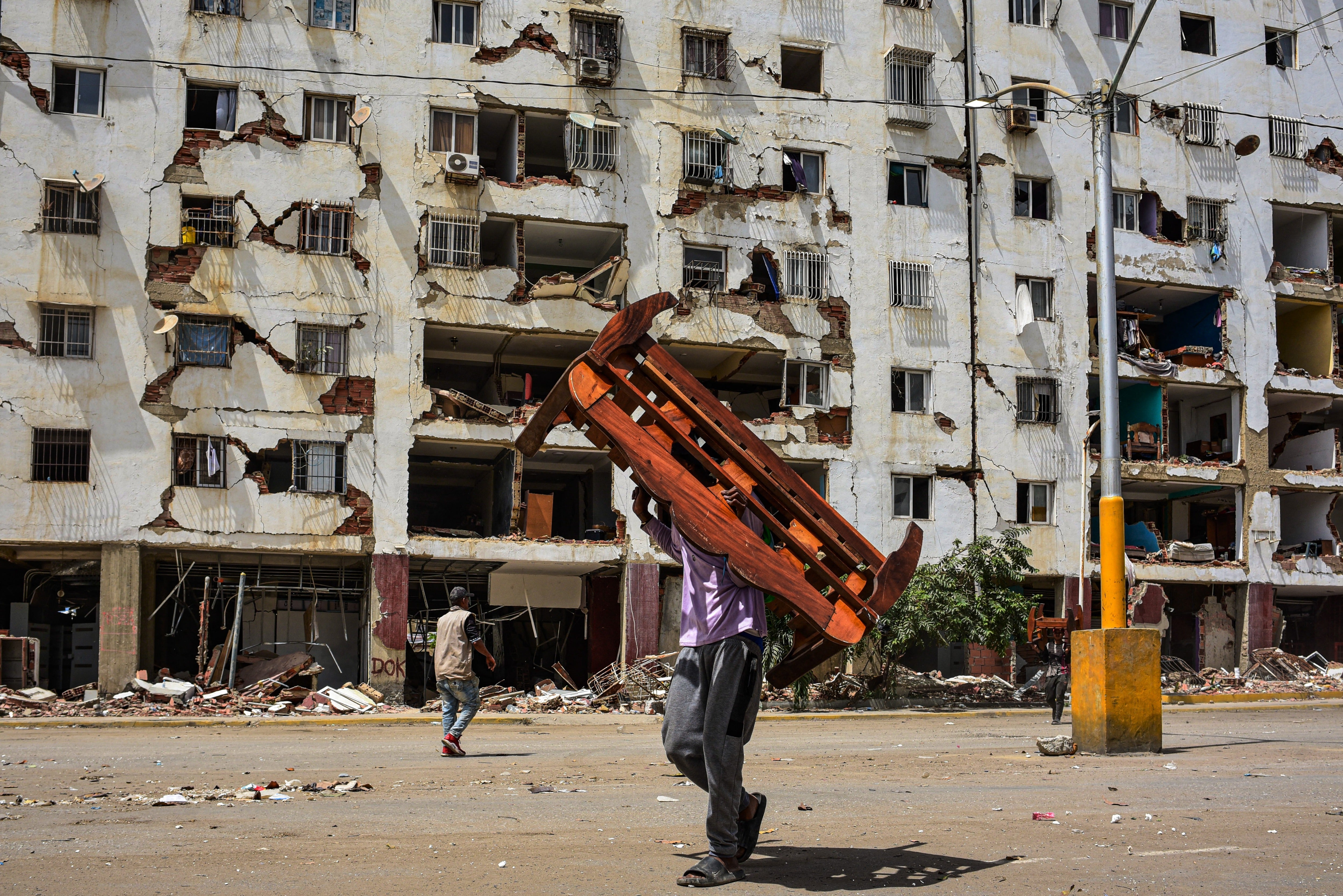 A man carries a piece of furniture salvaged from his apartment in one of the buildings affected by the June 24 earthquake in La Guaira, Venezuela
