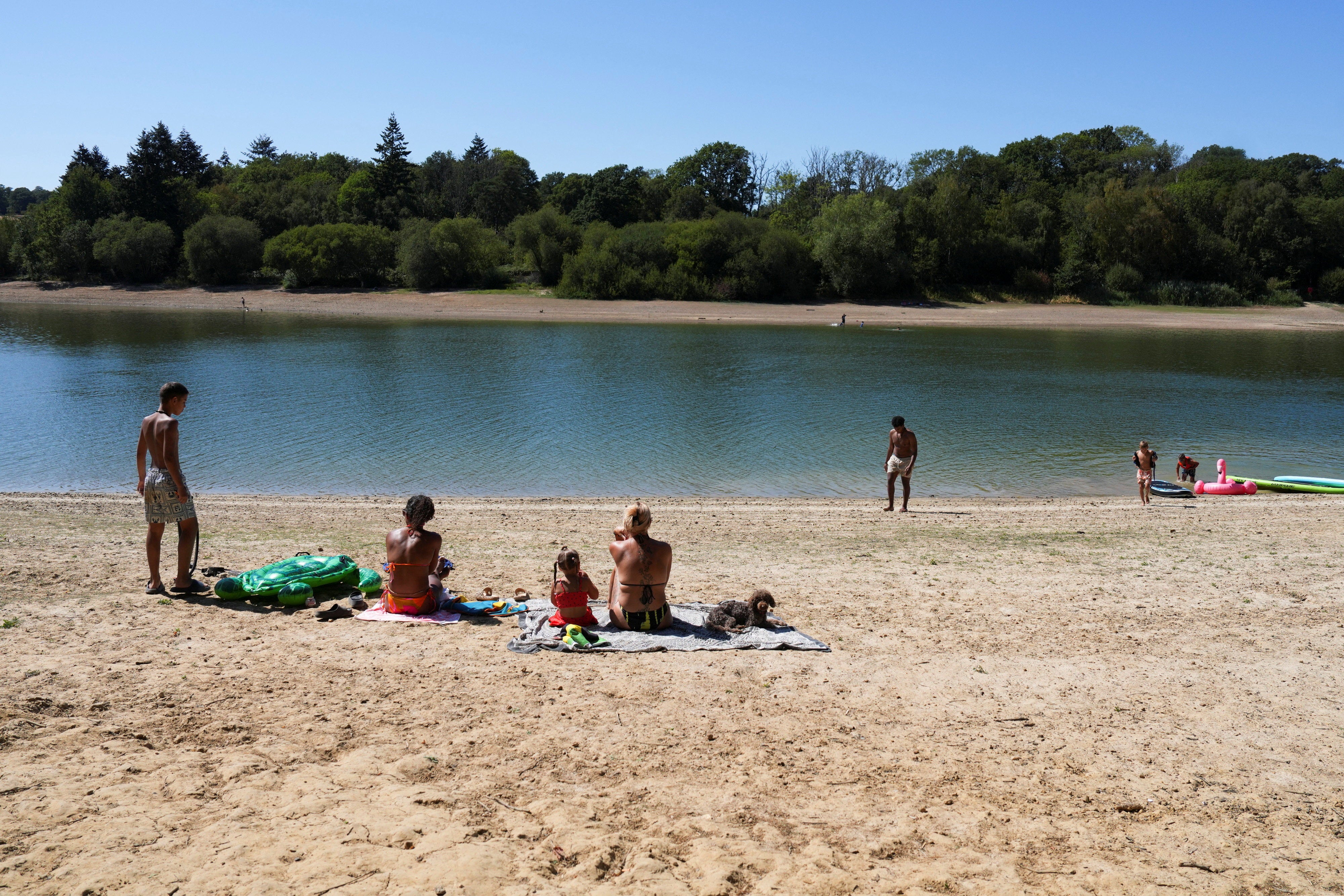 People enjoy at Ardingly Reservoir as water levels recede after Britain’s Environment Agency declared the East Midlands, Lincolnshire and Northamptonshire, Kent, East Sussex, and Solent and South Downs regions in drought during the fifth heatwave of the year, near Ardingly, south‑east Britain, August 12, 2026