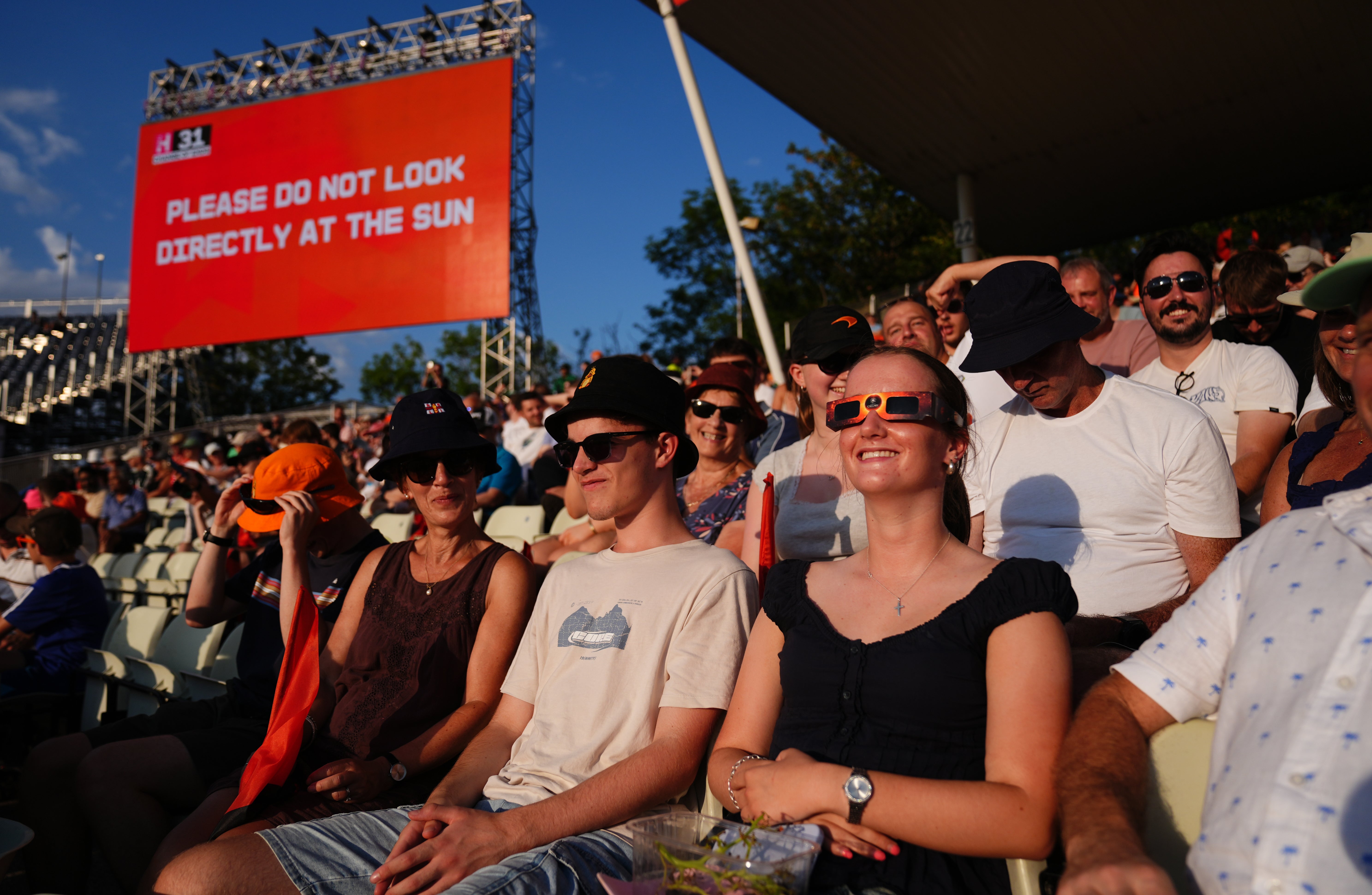 Spectators in the stands uses special eclipse glasses to watch the solar eclipse (Jacob King/PA)