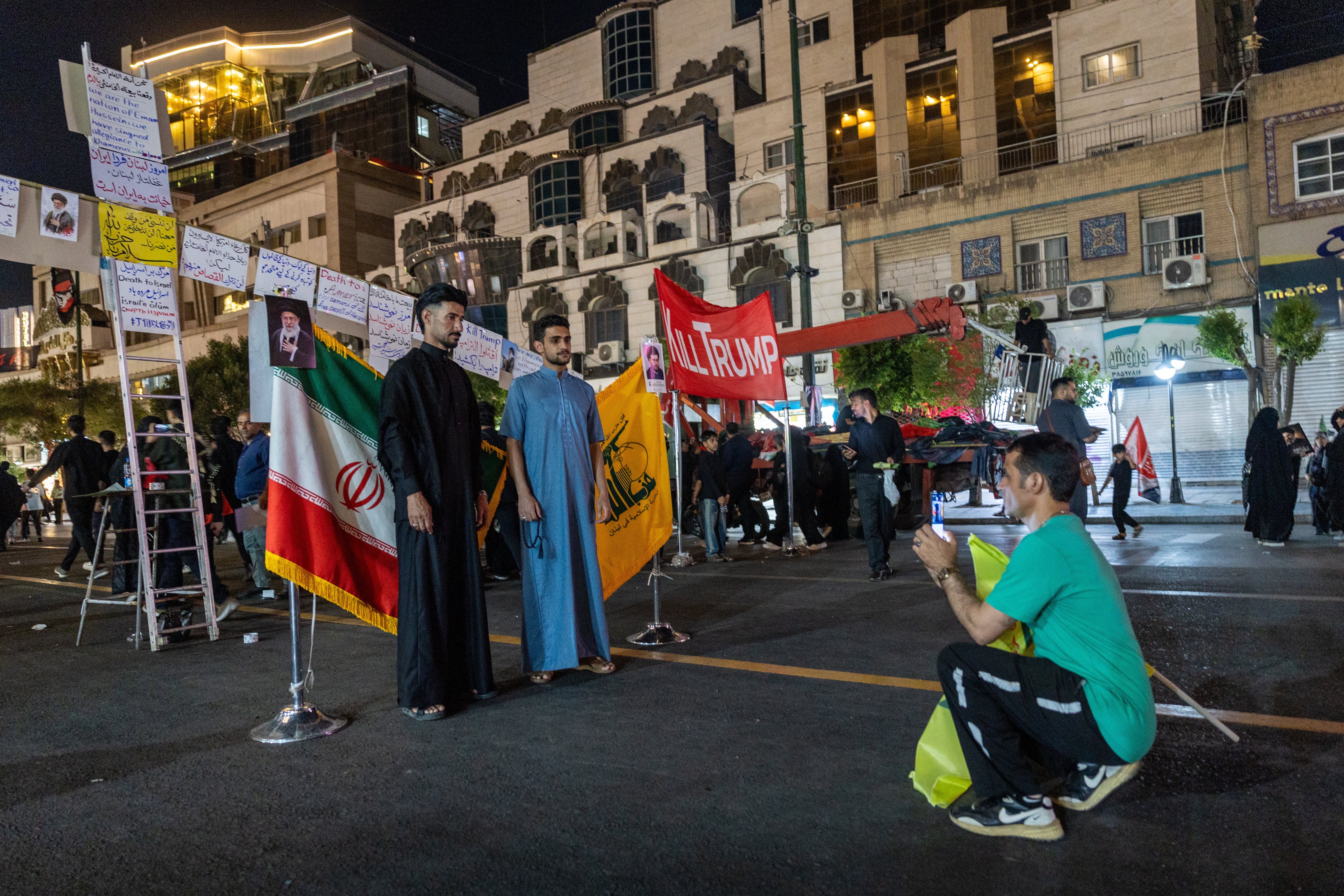Mourners pose for keepsake photos in front of the Iranian flag and the flag of Hezbollah in Lebanon near the Imam Reza Shrine (Getty)