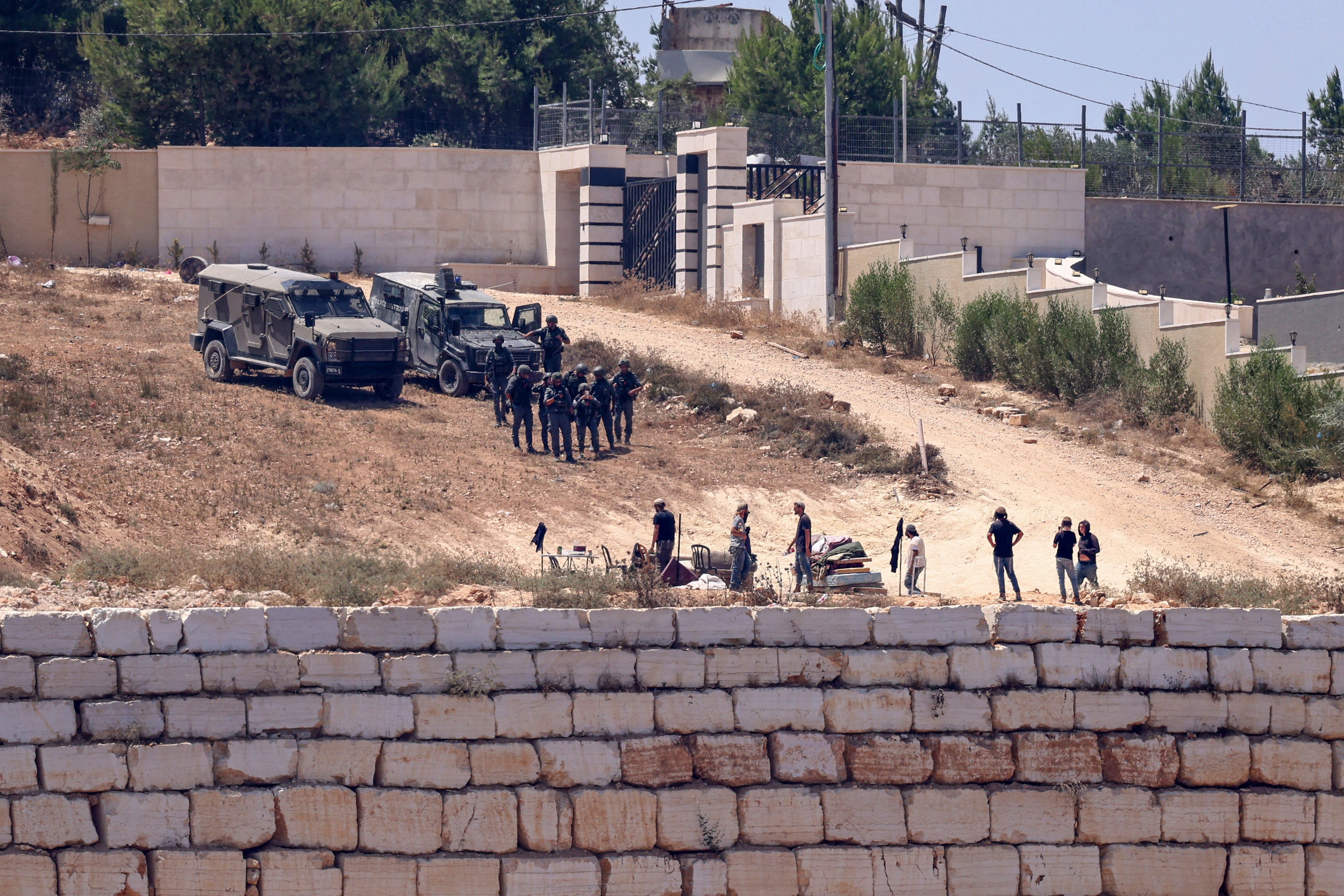 Israeli soldiers (top) stand guard next to settlers in front of the Palestinian houses in the village of Qusra, south of Nablus, in the occupied West Bank (AFP/Getty)