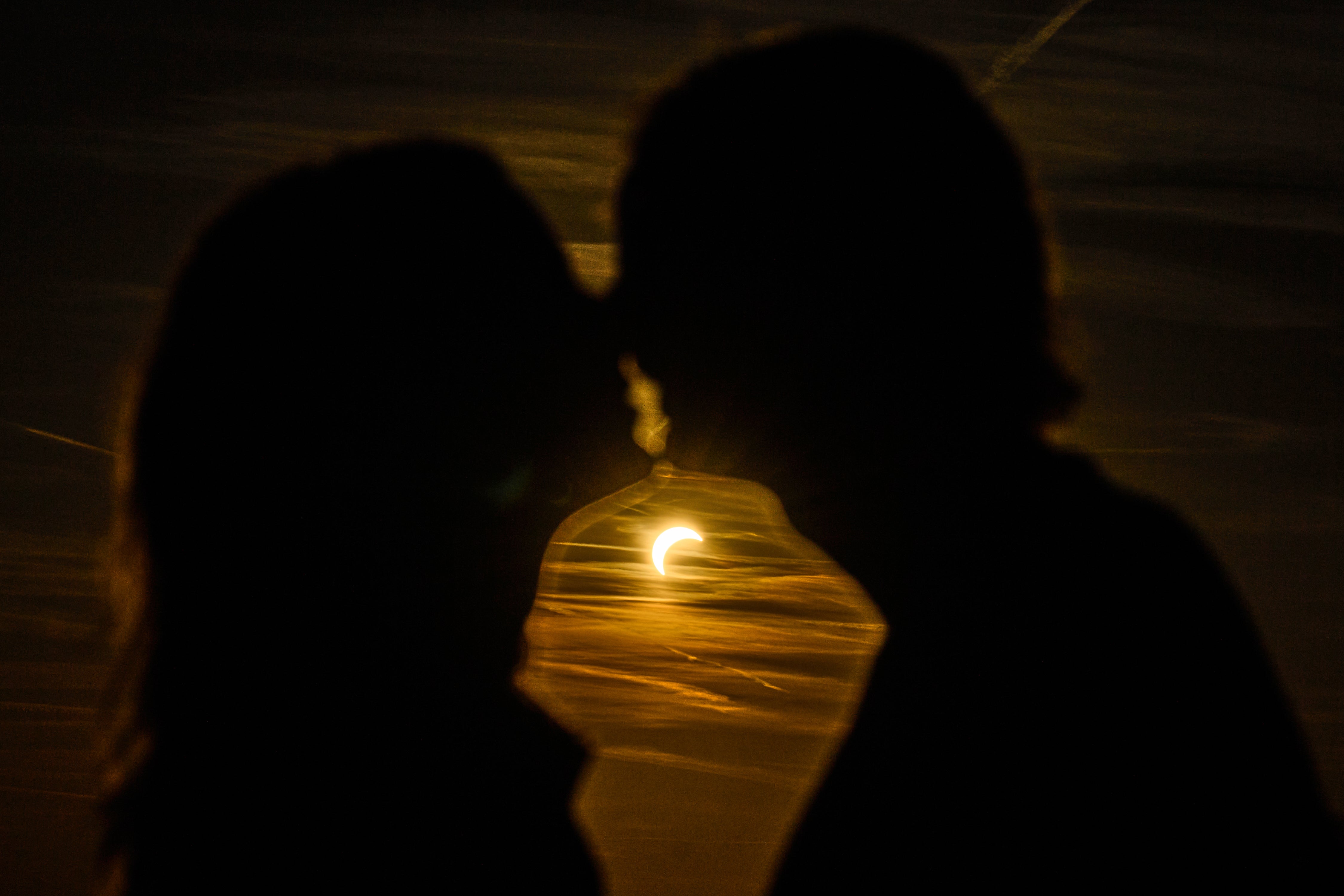 A couple kissees during a partial solar eclipse at the former airport Tempelhof in Berlin, Germany, Wednesday, Aug. 12, 2026. (AP)