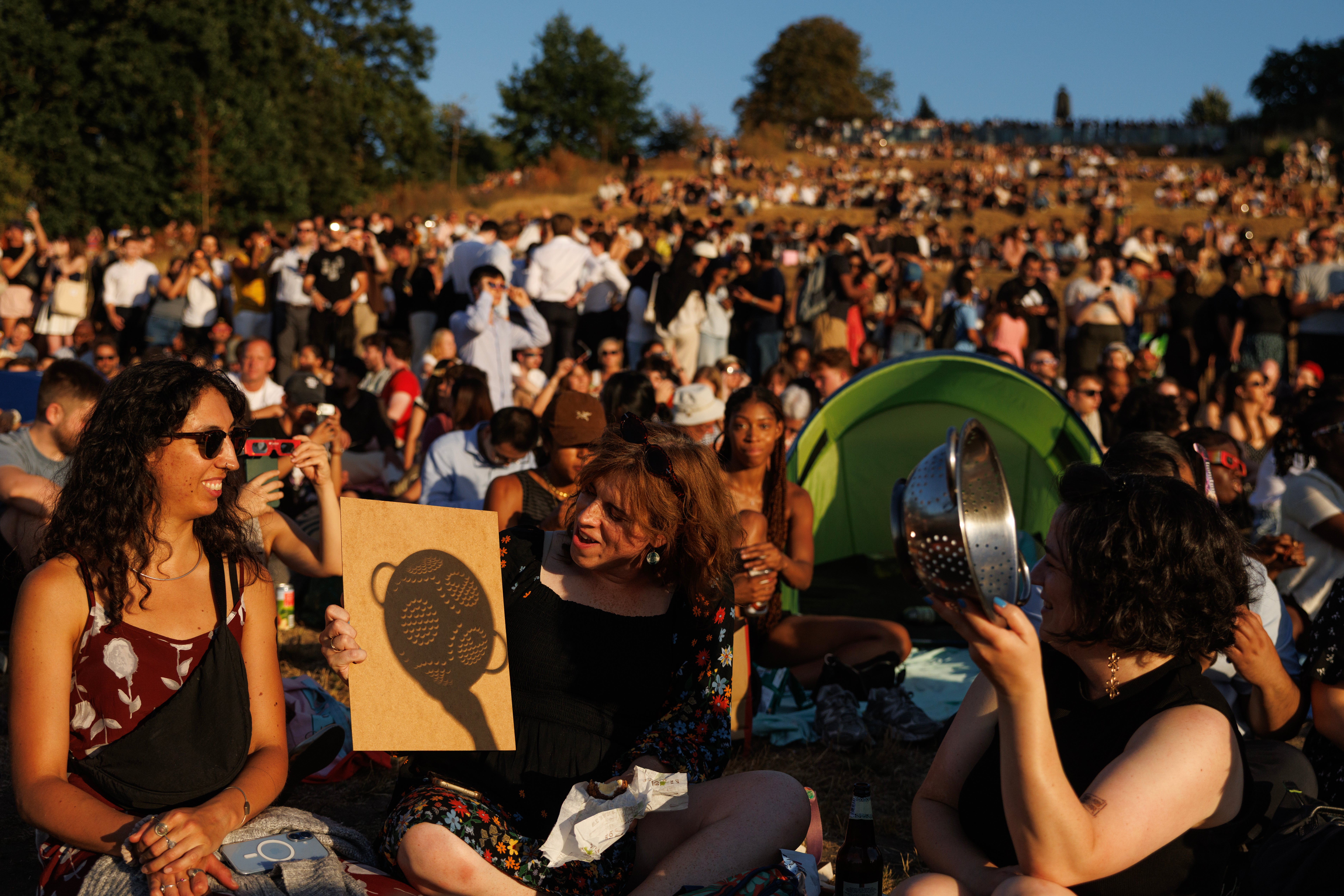 People gather to view the partial solar eclipse in Greenwich Park