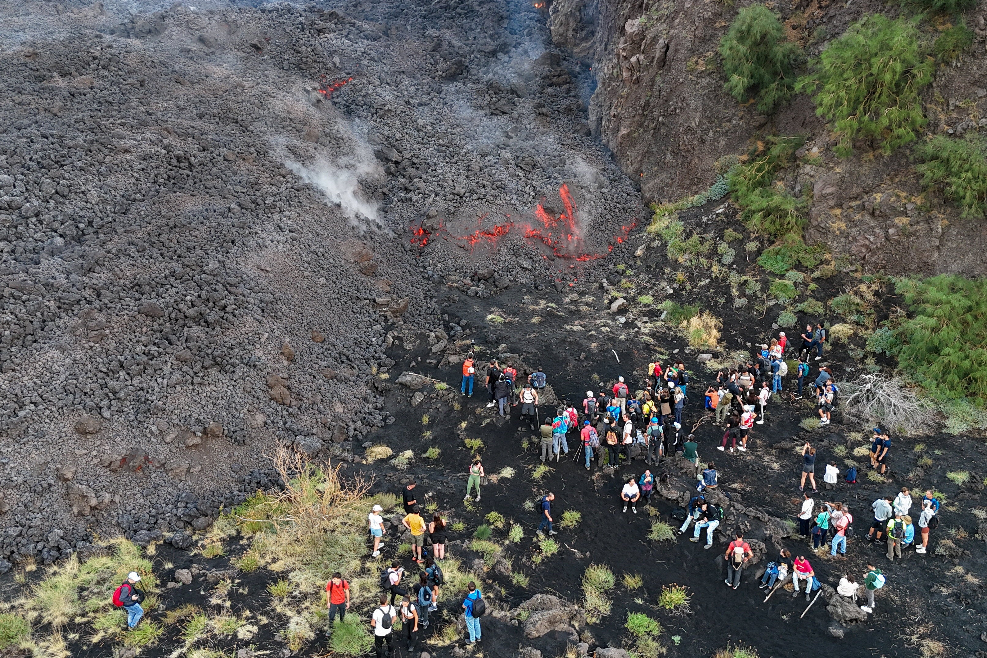 A drone view of people observing a volcanic eruption at Mount Etna