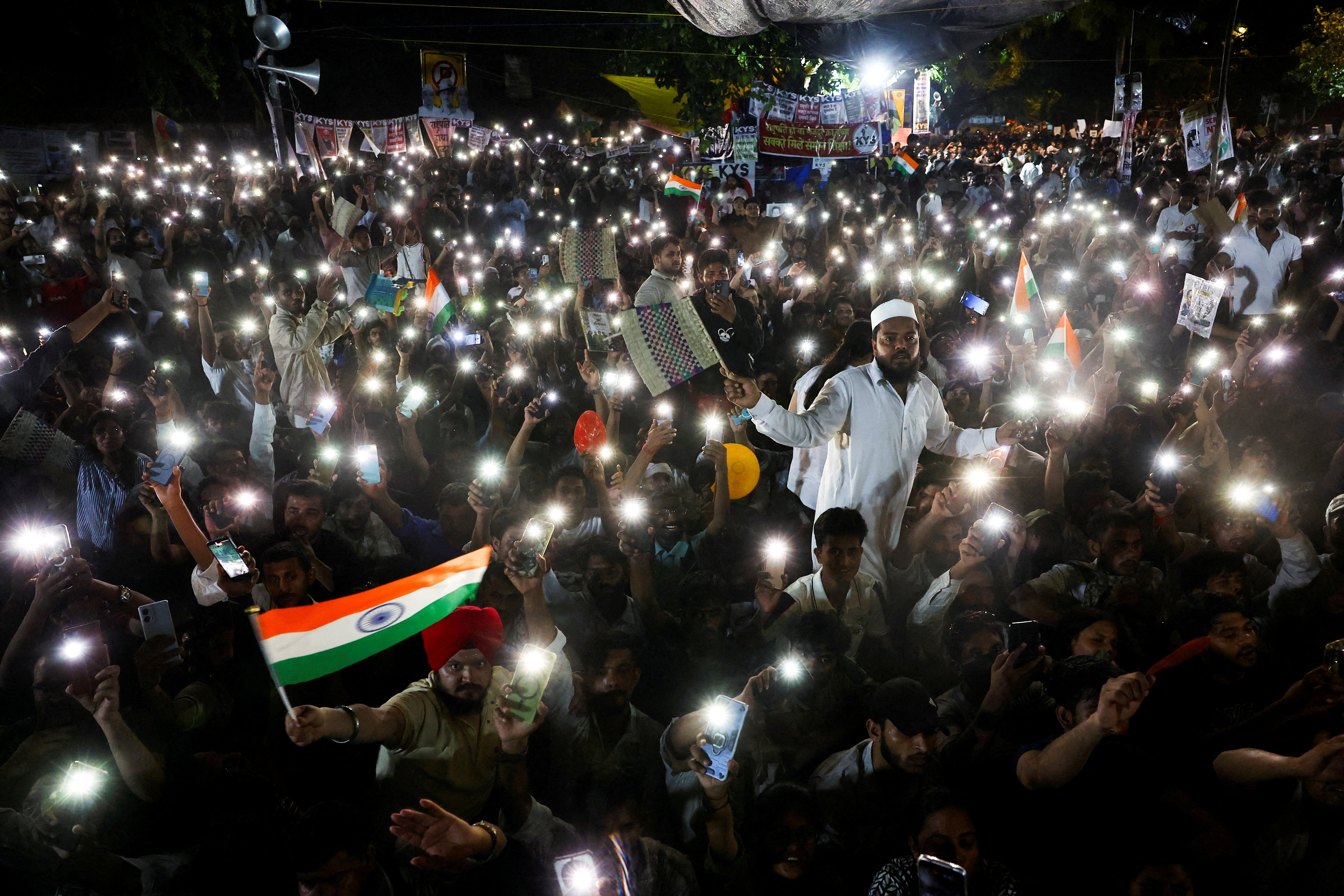 Supporters of the Cockroach Janta Party (CJP) chant slogans and wave their mobile phones with their flashlights on (Reuters)