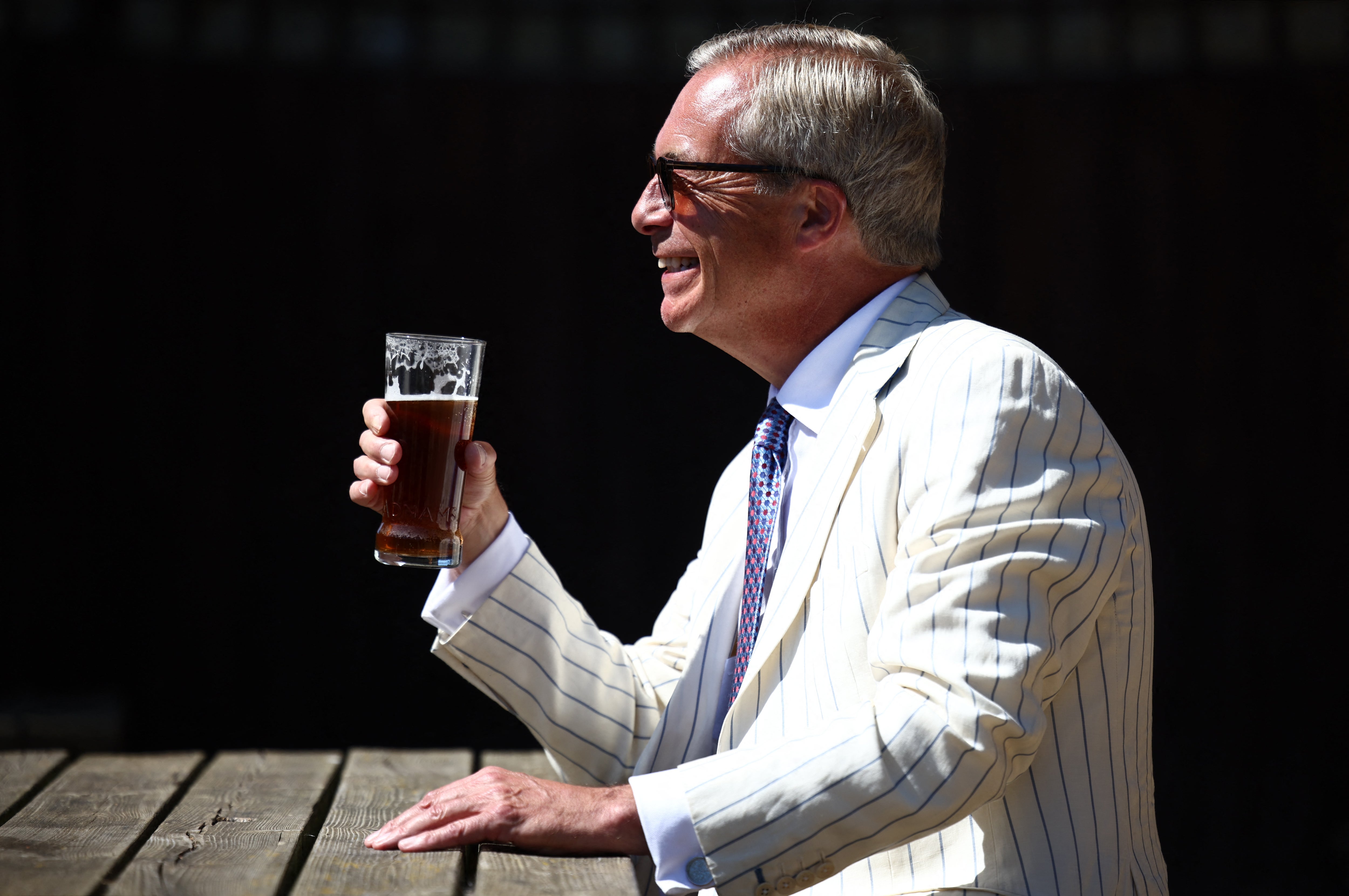 Reform UK leader Nigel Farage sits and poses with a pint in the garden of The Ship pub after casting his vote in the Clacton by-election (AFP/Getty)
