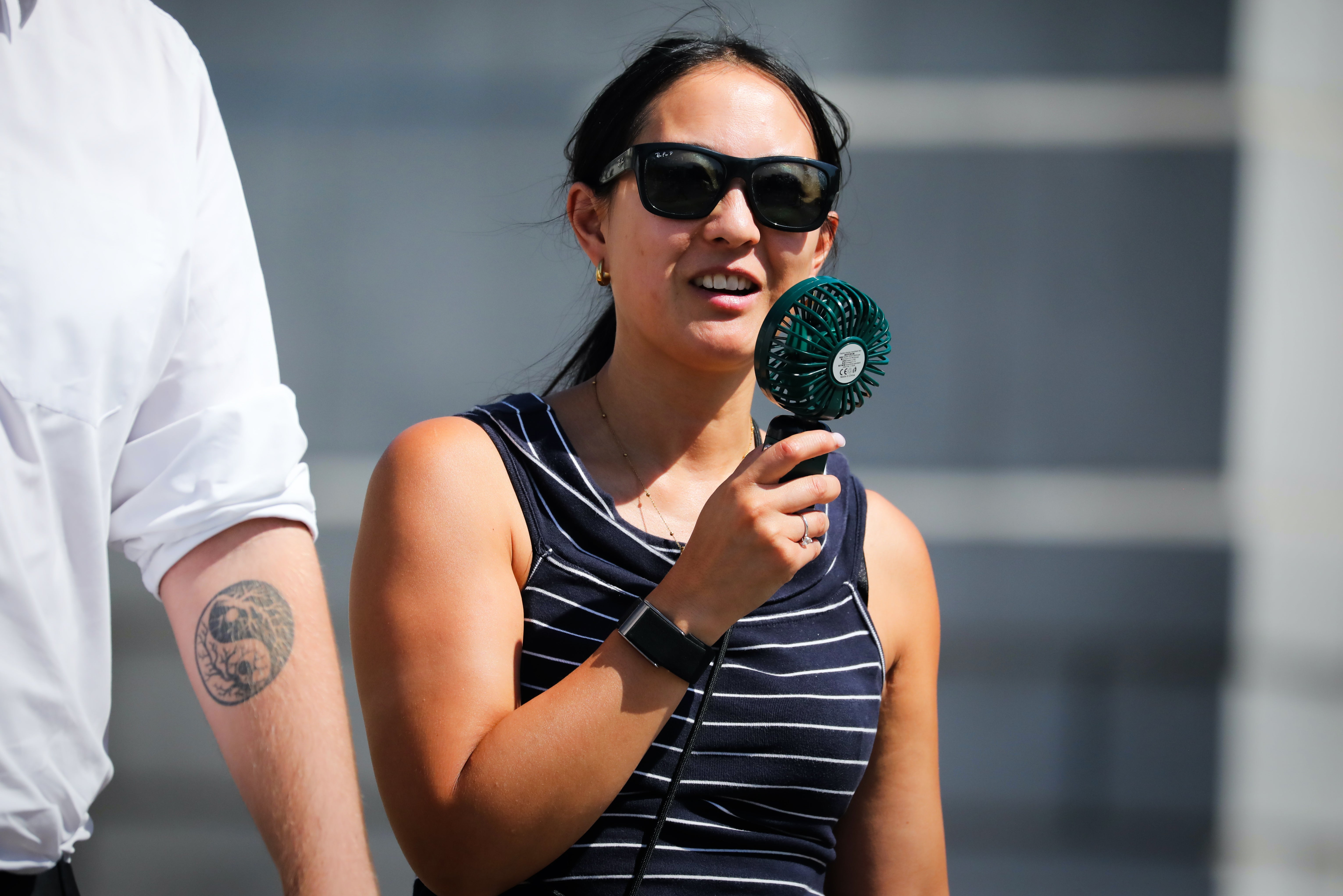 A person uses a fan to cool down in Trafalgar Square