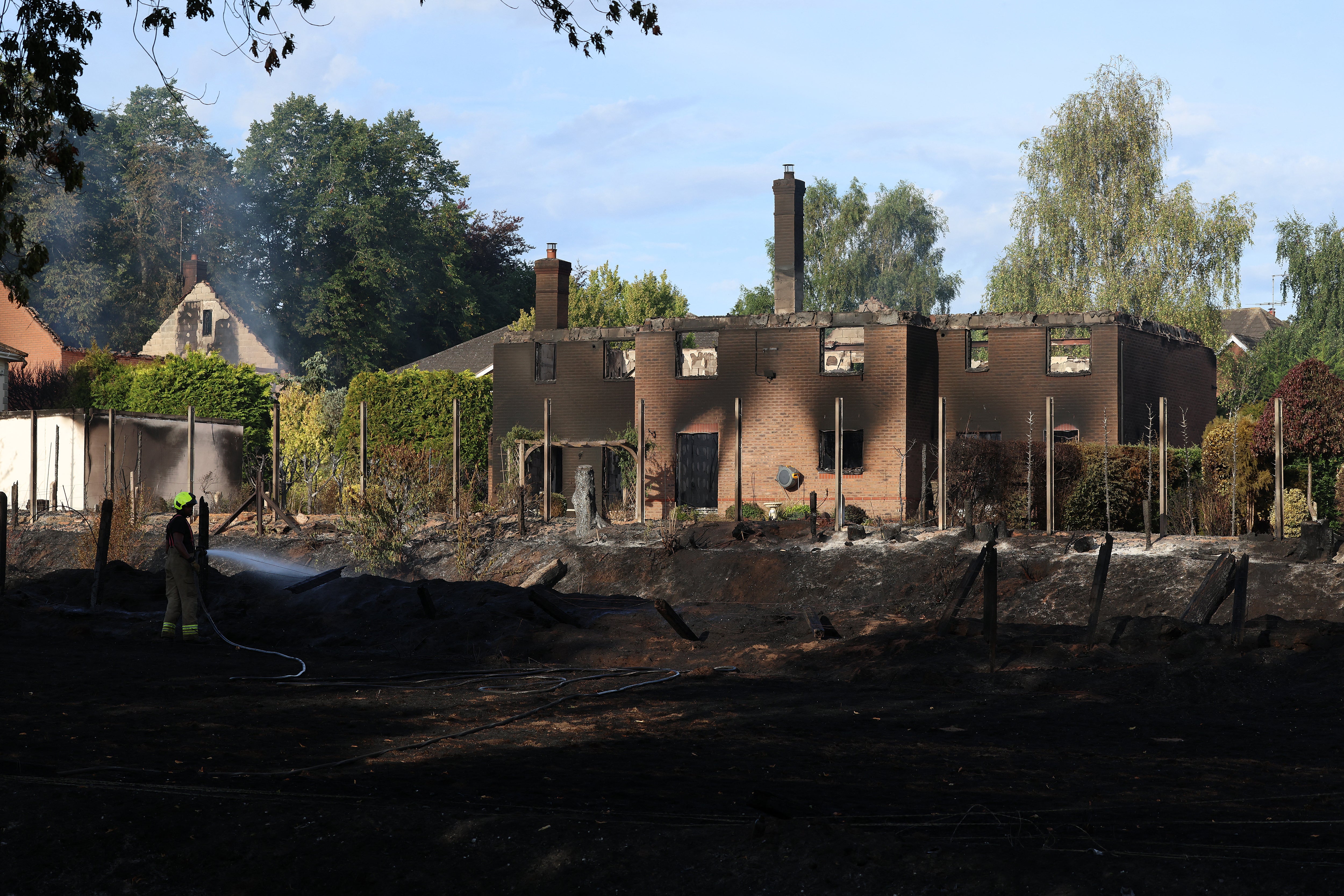 Firefighters work at the site of a fire-damaged house in Stourbridge, south-west of Birmingham, central England on August 14, 2026