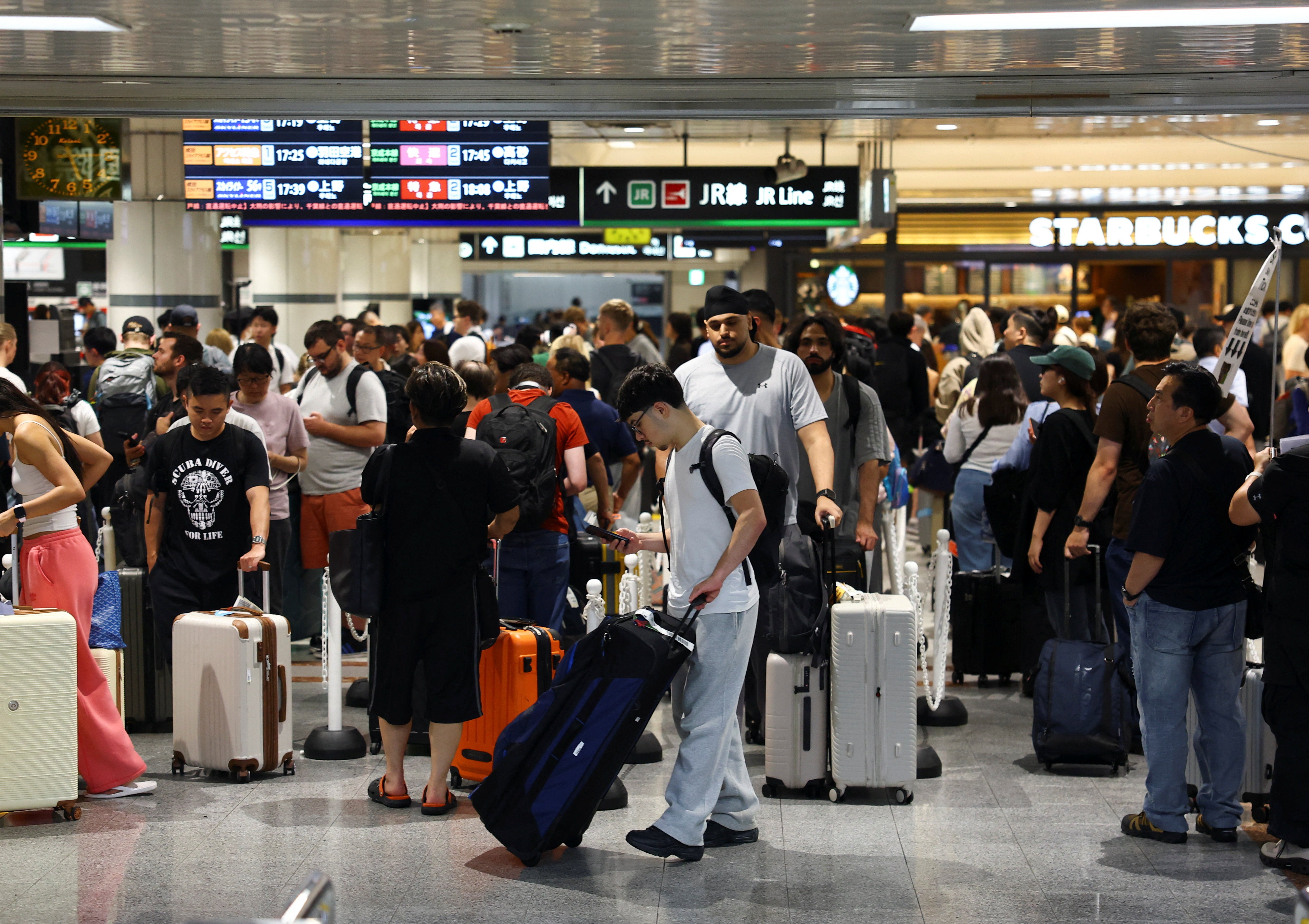 Passengers queue at a train station at Narita International Airport, in Narita (Reuters)