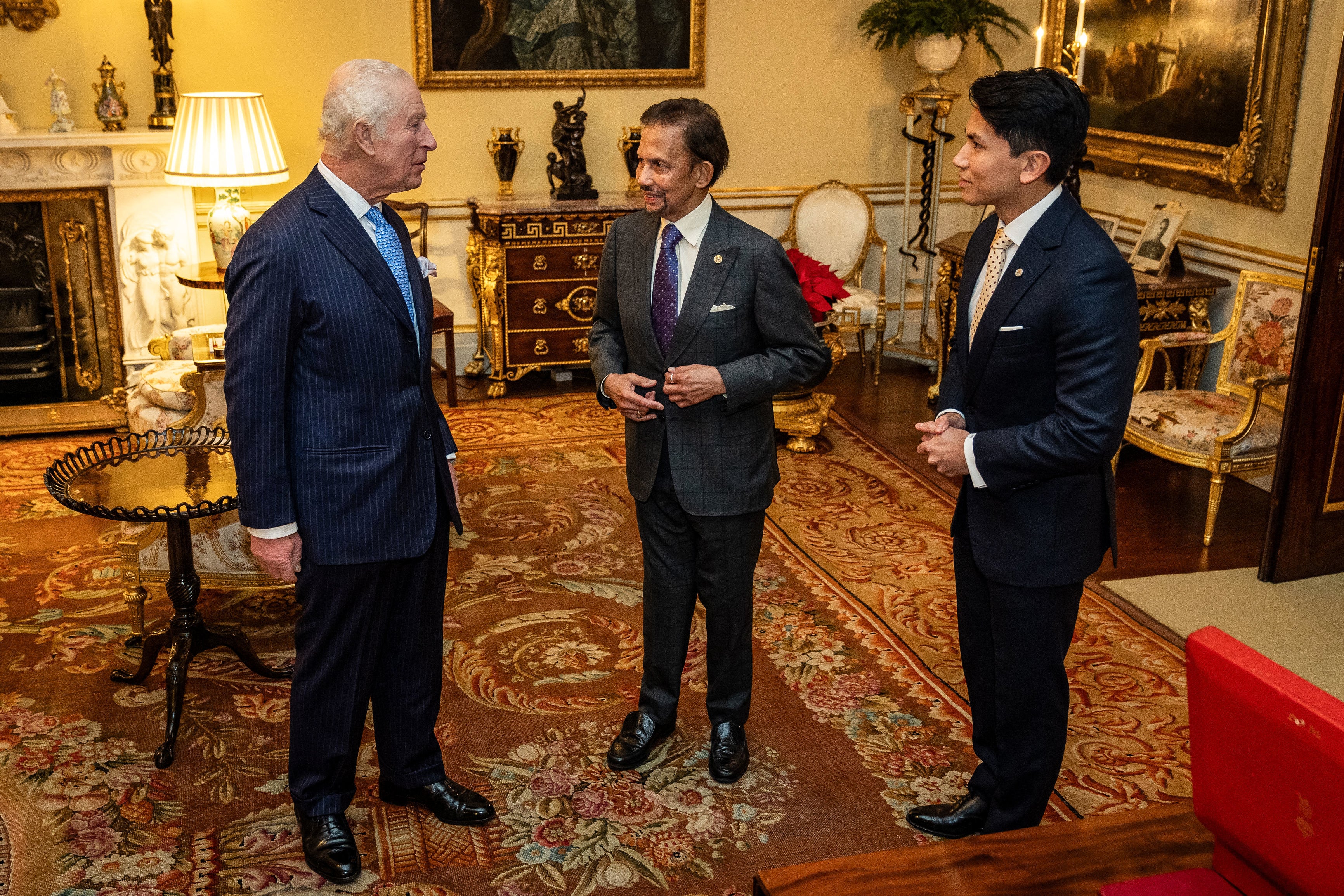 King Charles, left, meets with Brunei's Sultan Hassanal Bolkiah, centre, and Prince Mateen Darussalam at Buckingham Palace in London on 18 December 2024 (AFP/Getty)
