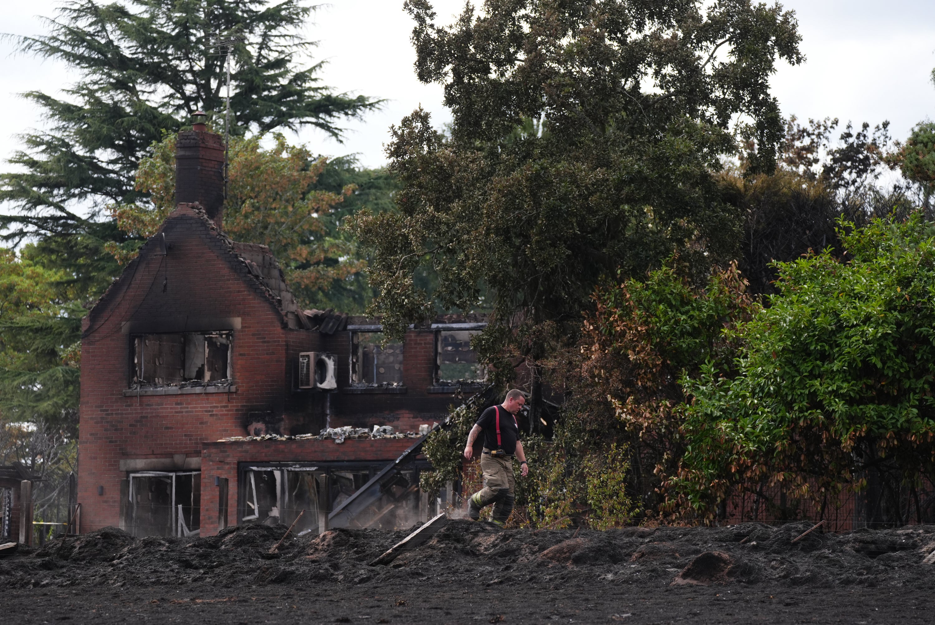 A firefighter checks the ground around the burnt out remains of a house following a huge blaze in Stourbridge, in the West Midlands, which forced some people to flee after it started tearing through homes