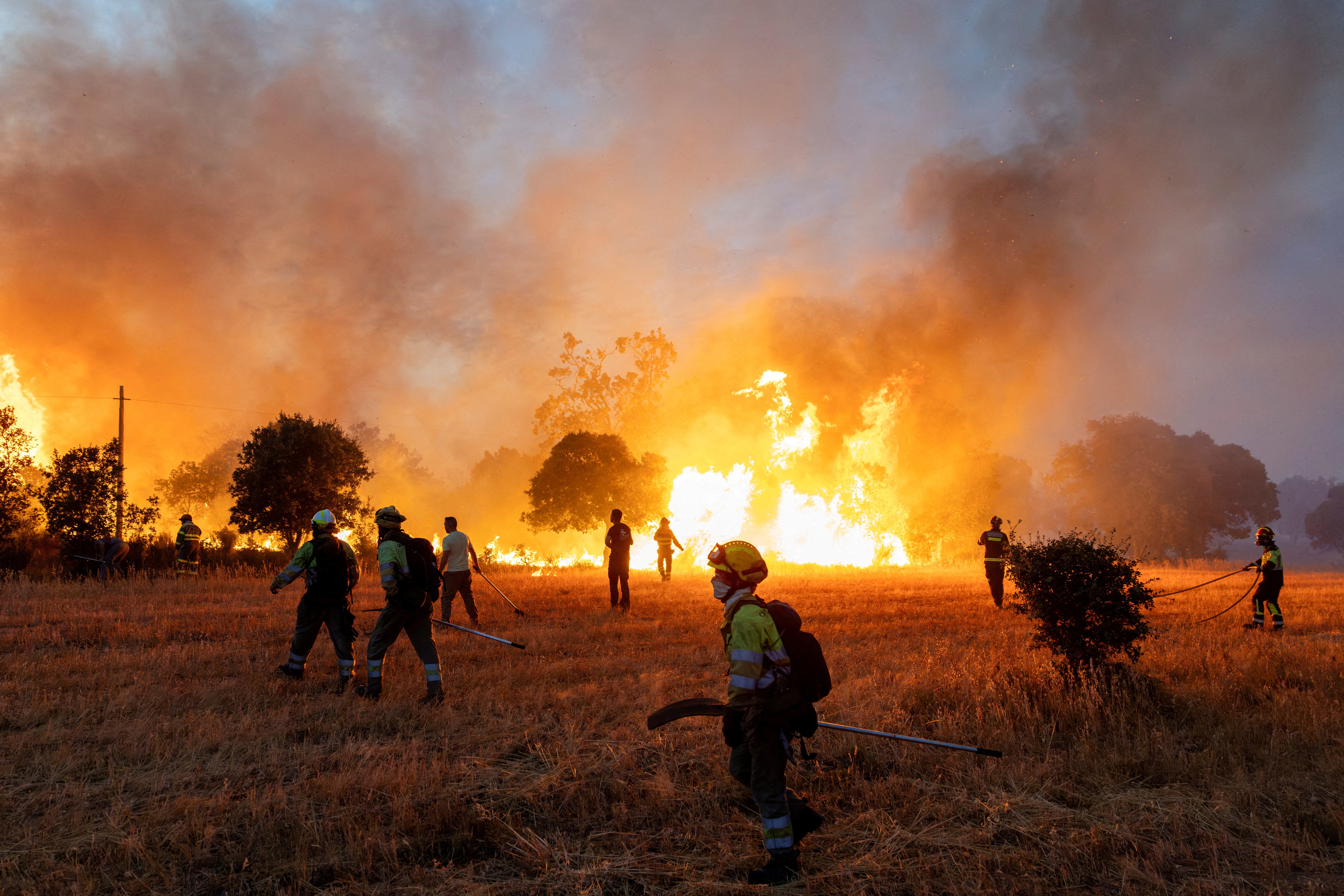 Residents and firefighters work to extinguish an advancing wildfire near Formariz in Zamora province, Spain