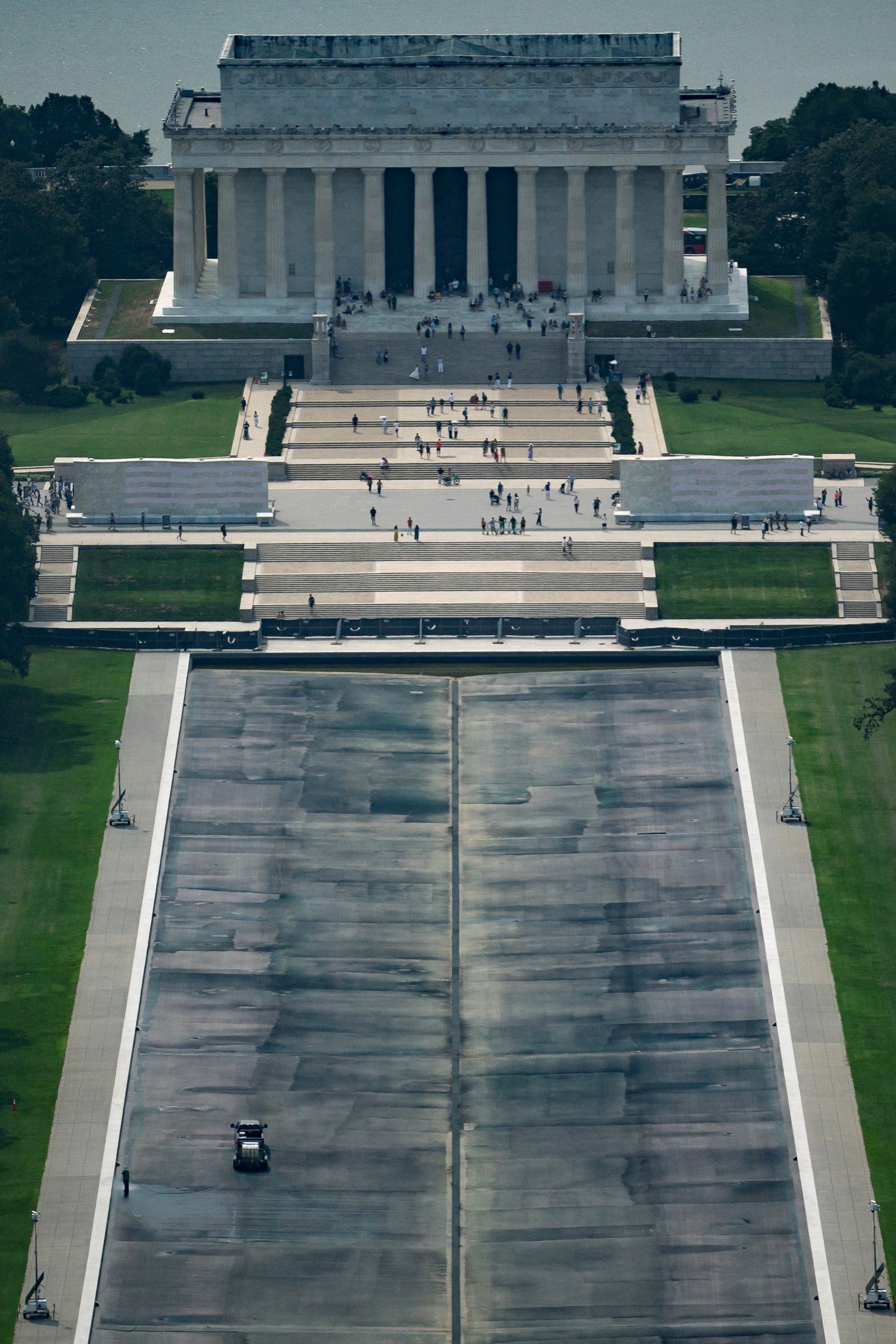 Construction crews continue work on the Lincoln Memorial Reflecting Pool on Thursday after it was once again drained for repairs stemming from what President Donald Trump has called ‘vandalism’ but ...