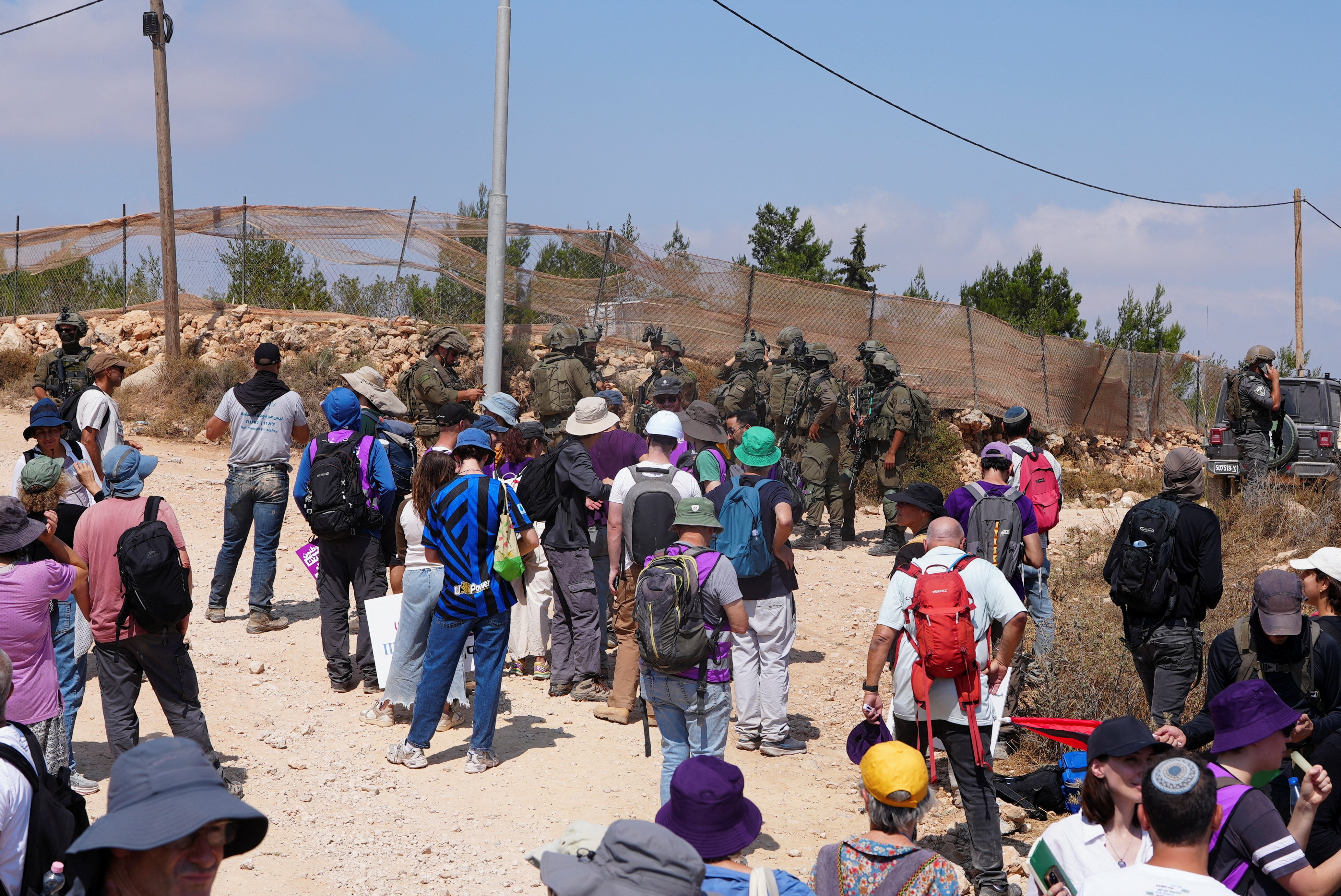 Palestinian, Israeli and foreign activists try to approach a Palestinian house which was besieged by Israeli settlers