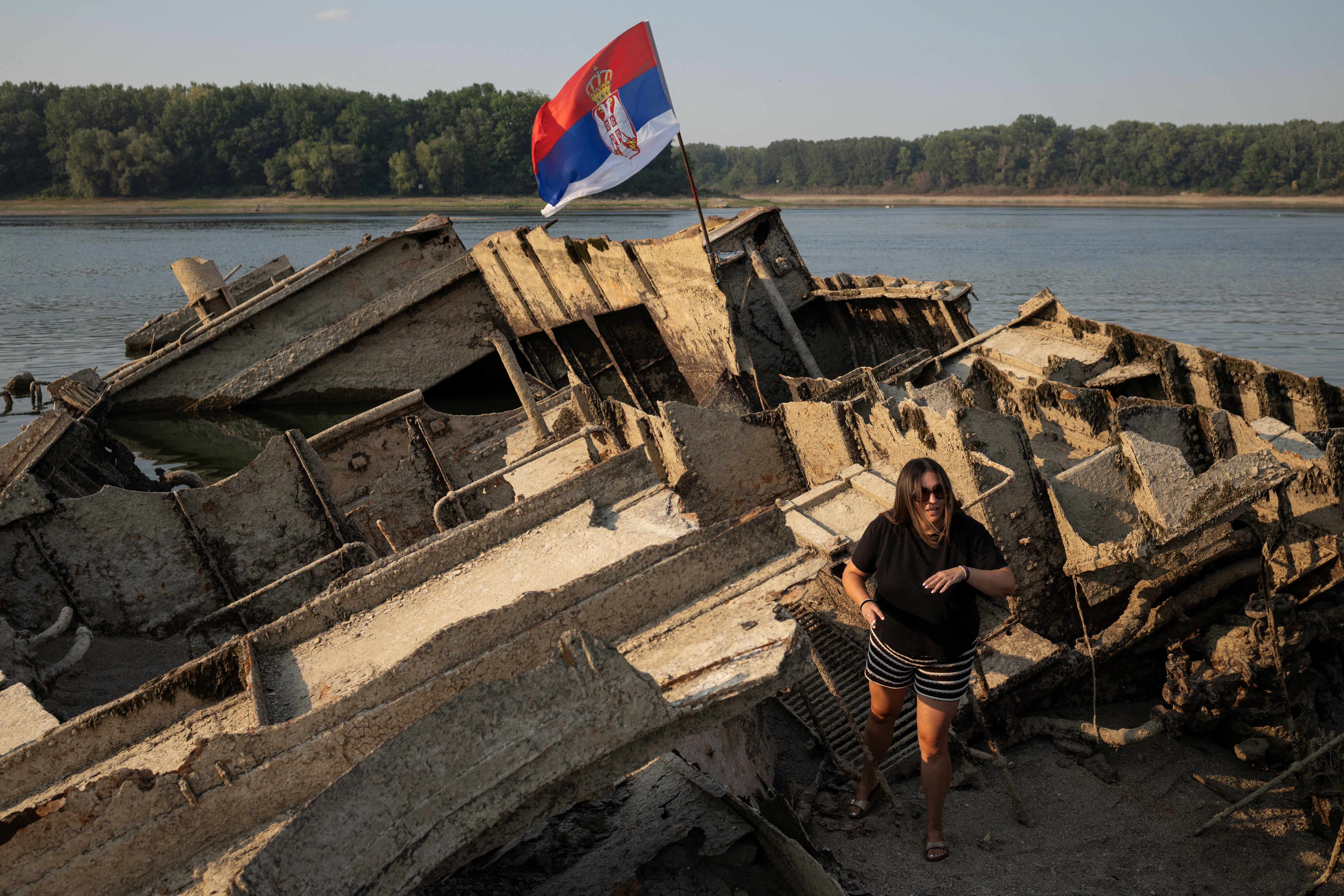 A woman stands on a sunken German warship from World War II, exposed due to low Danube river levels caused by drought and extreme heat near Prahovo