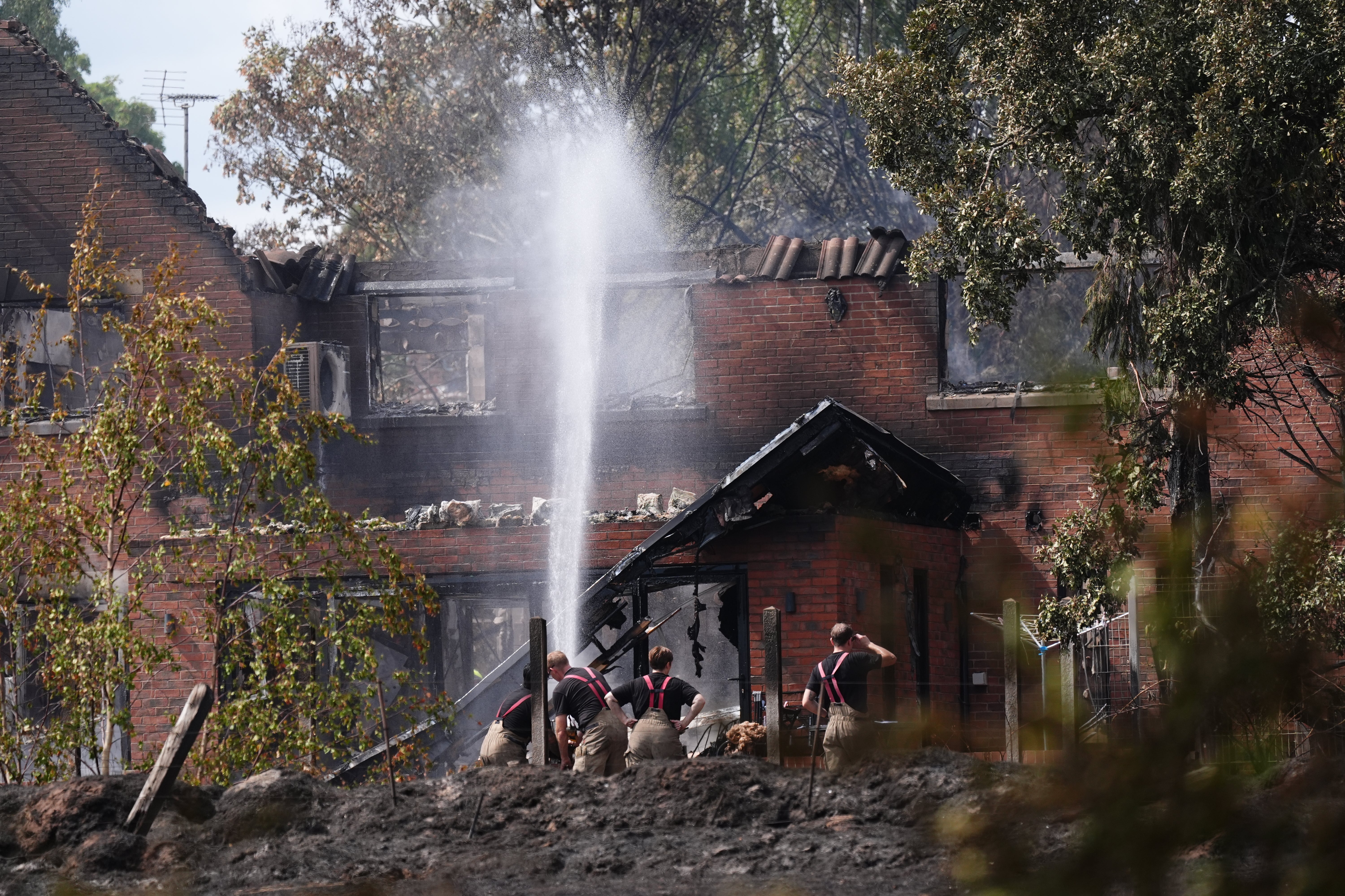 Firefighters spraying water onto the burnt out remains of a house following a huge blaze in Stourbridge (PA Wire)