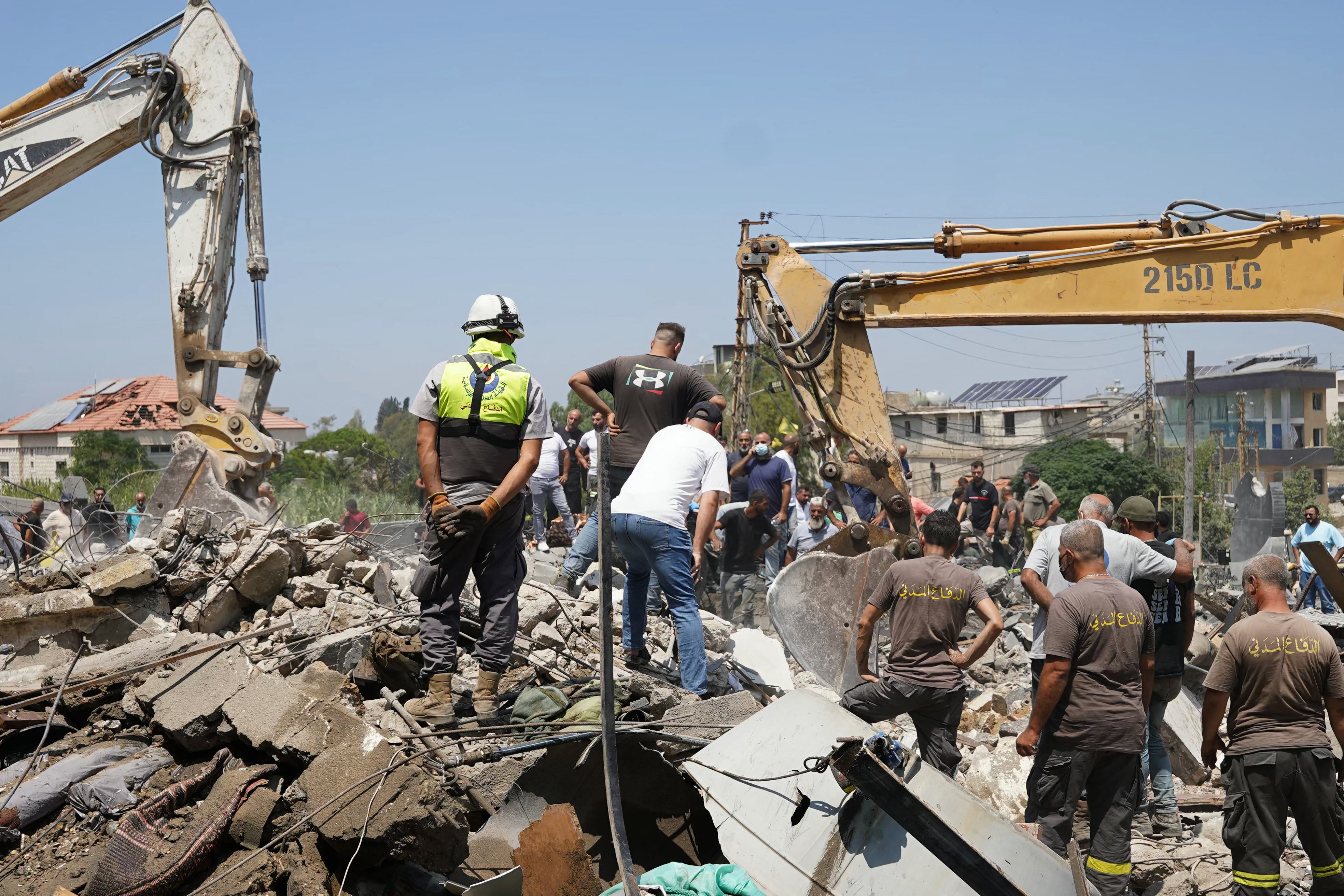 Heavy machinery, first aid responders and residents search the site of an Israeli airstrike in southern Lebanon