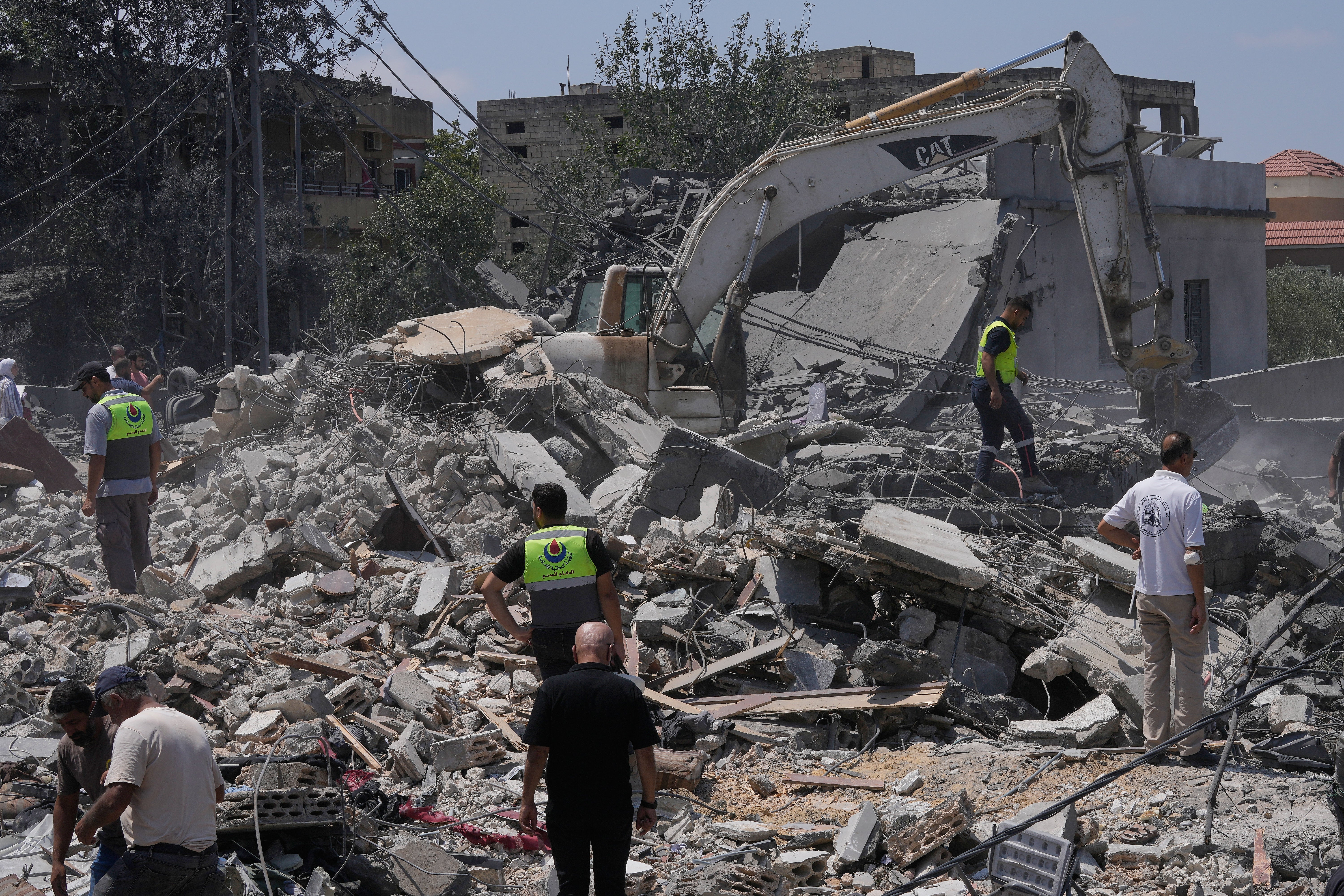 People and rescue workers gather on a destroyed house that was hit by an Israeli airstrike in southern Lebanon