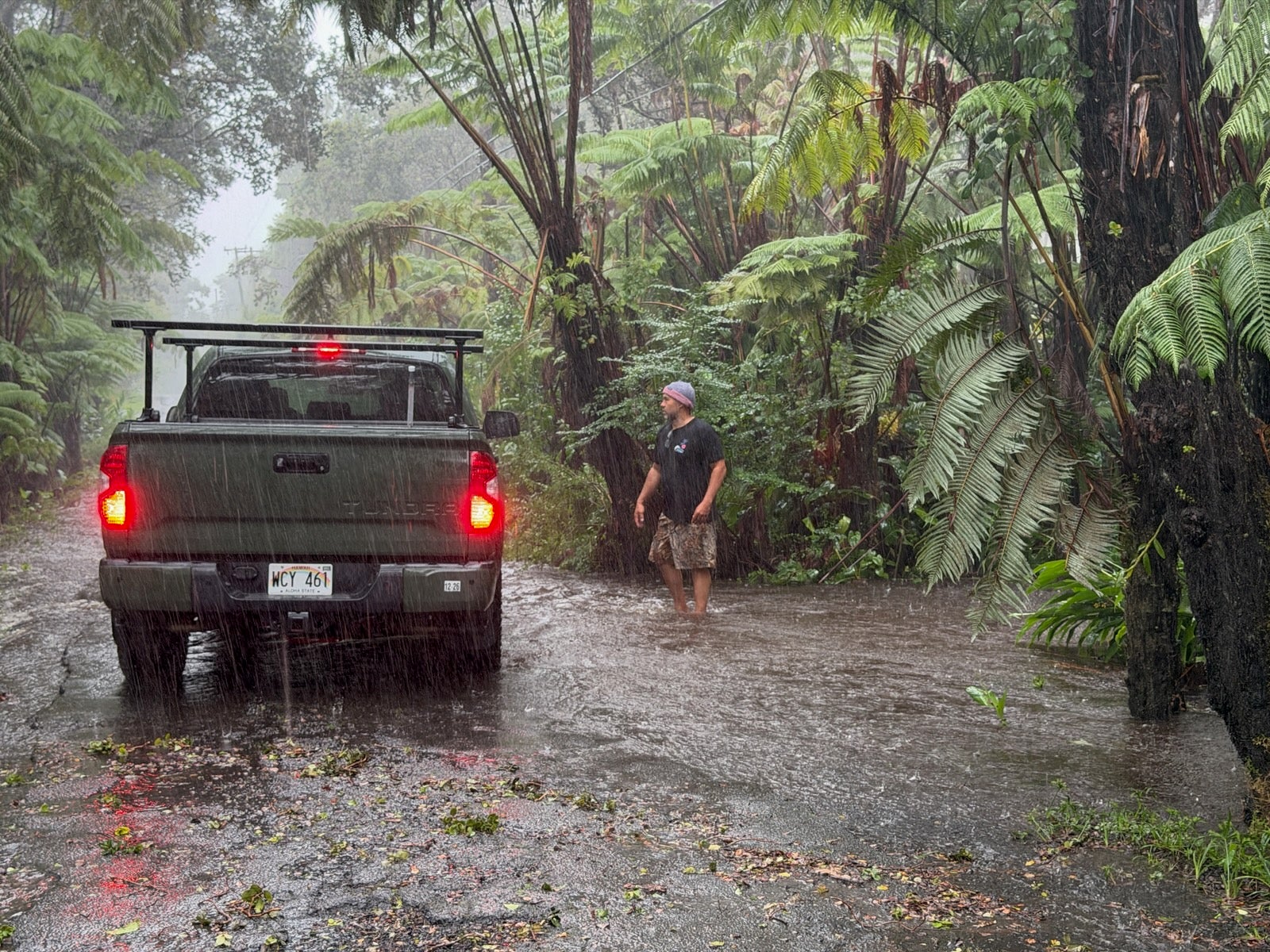A resident stops on a rural road as it floods in Volcano Village on Hawaii Island