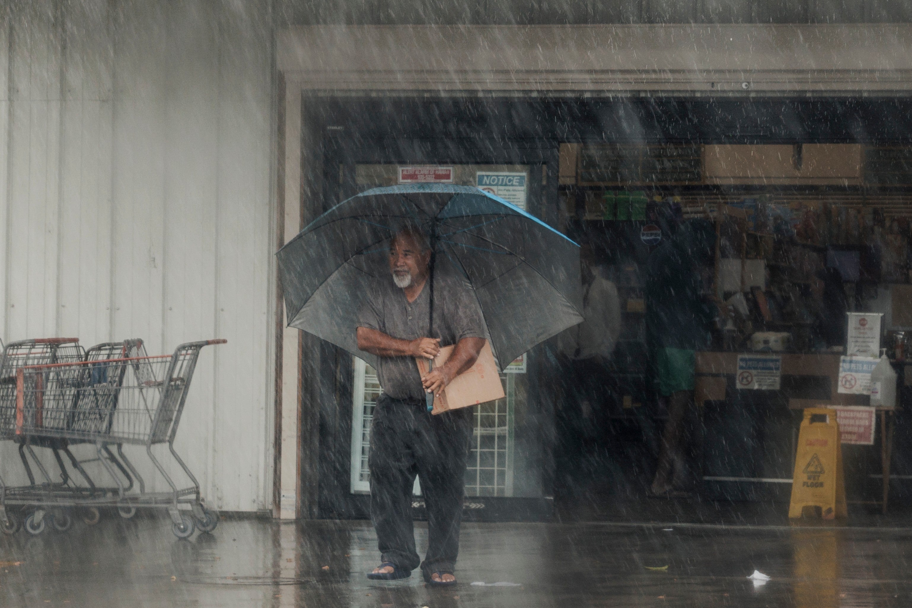A resident carries supplies during Hurricane Lala in Hawaii