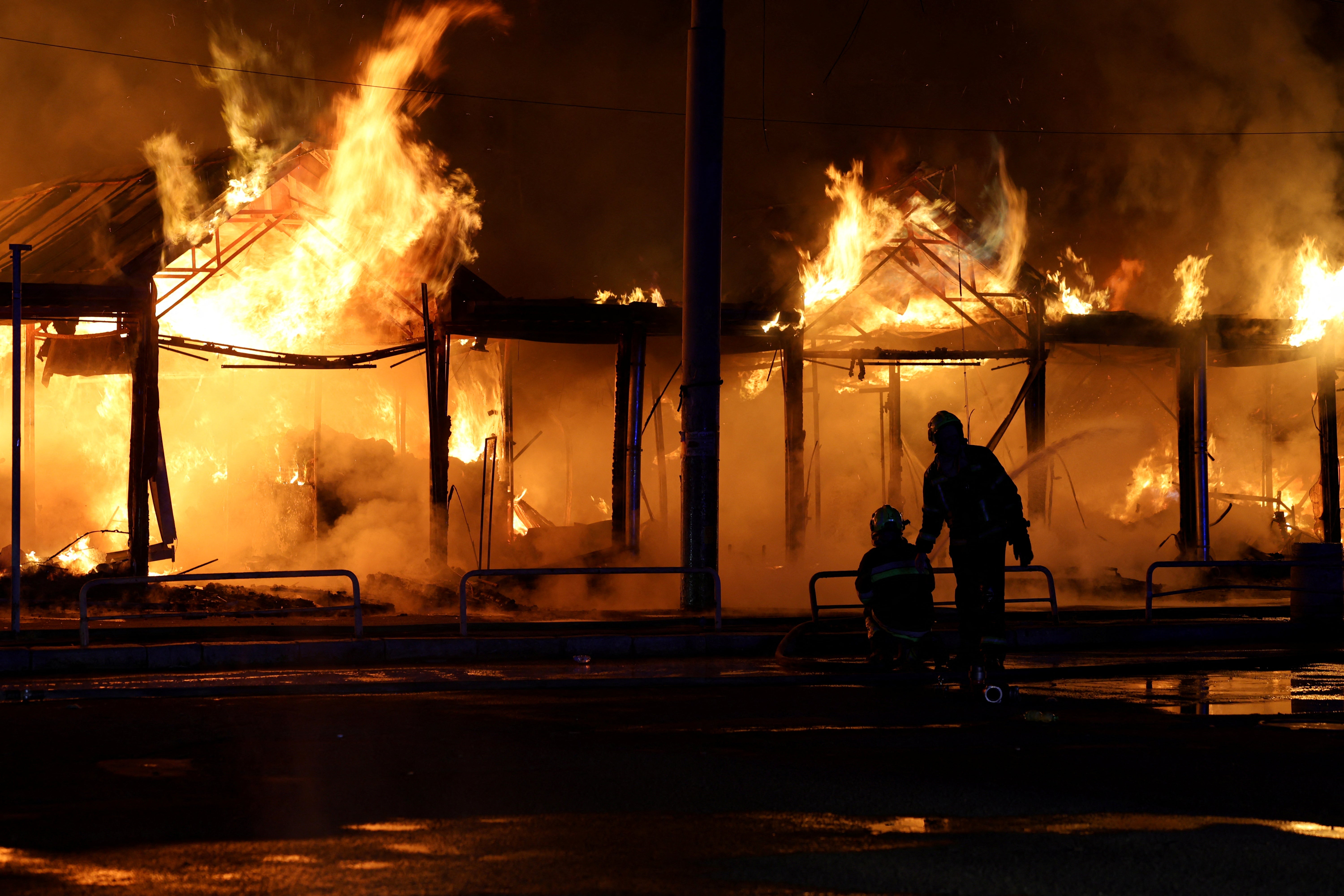 Ukrainian rescuers use a water hose as they work to extinguish a fire at the site of a Russian strike in Kyiv on August 16