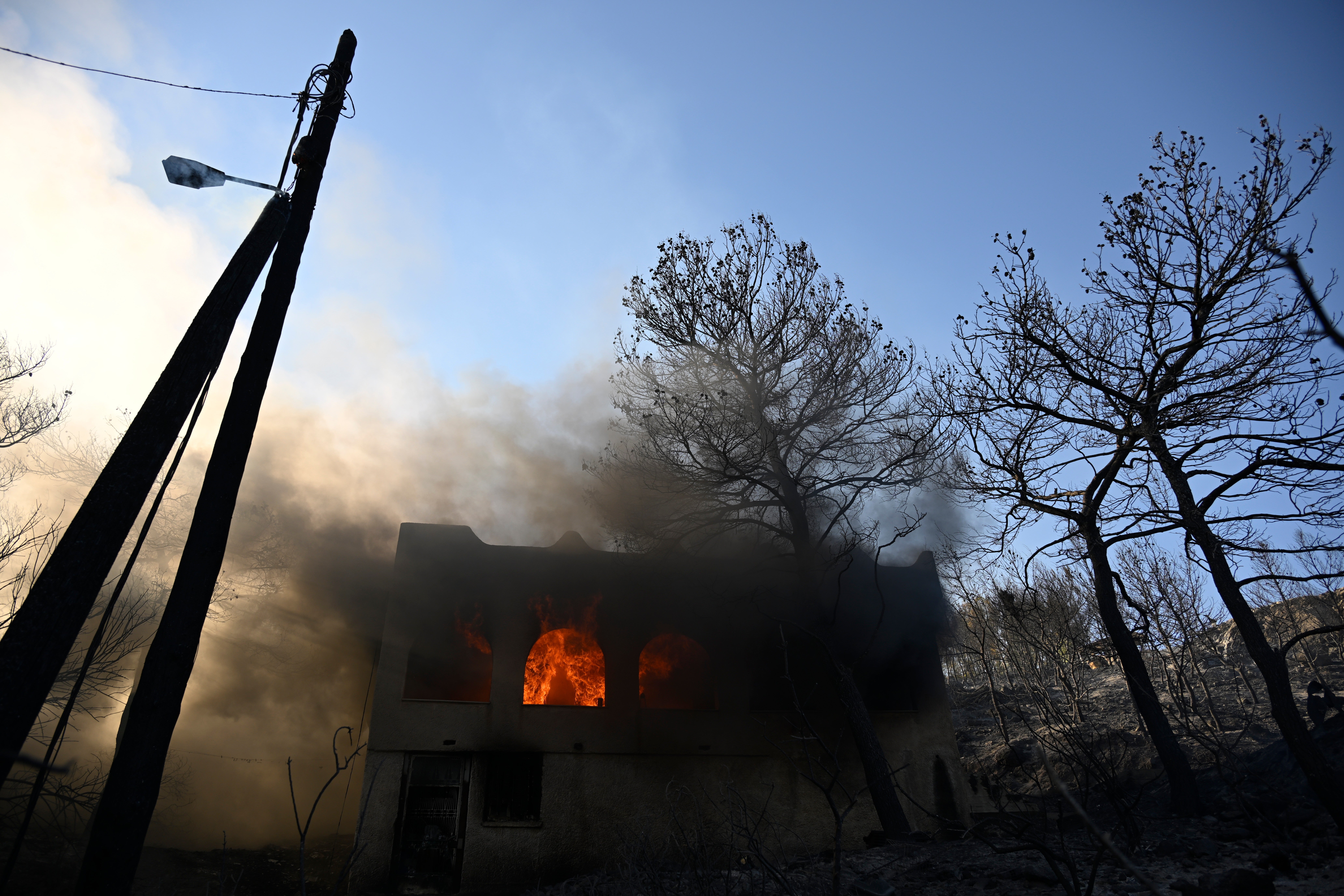 Flames burn in a house during a wildfire on the island of Salamina