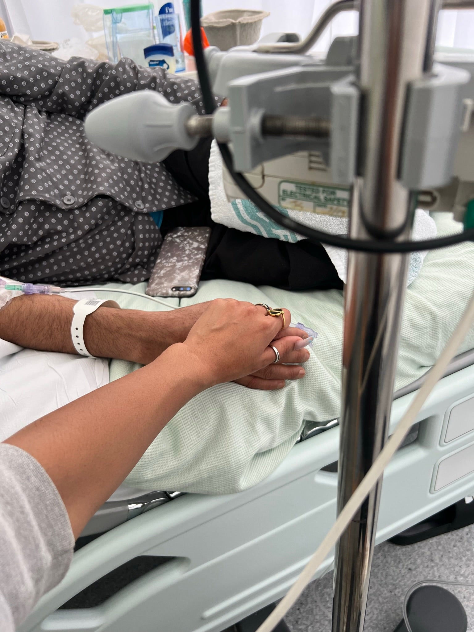 Zahida holding father’s hand in hospital bed
