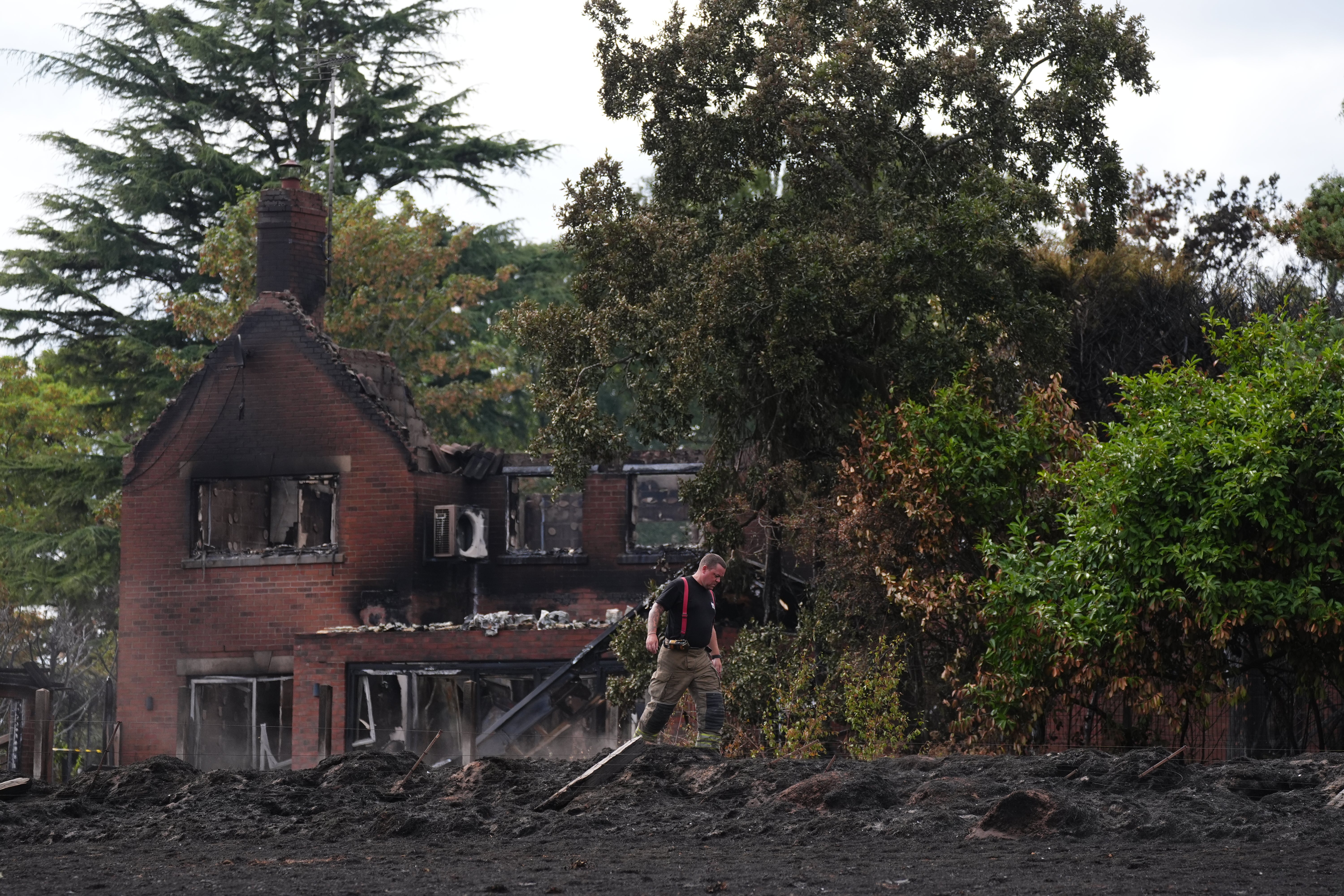 A firefighter outside the burnt out remains of a house in Stourbridge, in the West Midlands (Jacob King/PA)