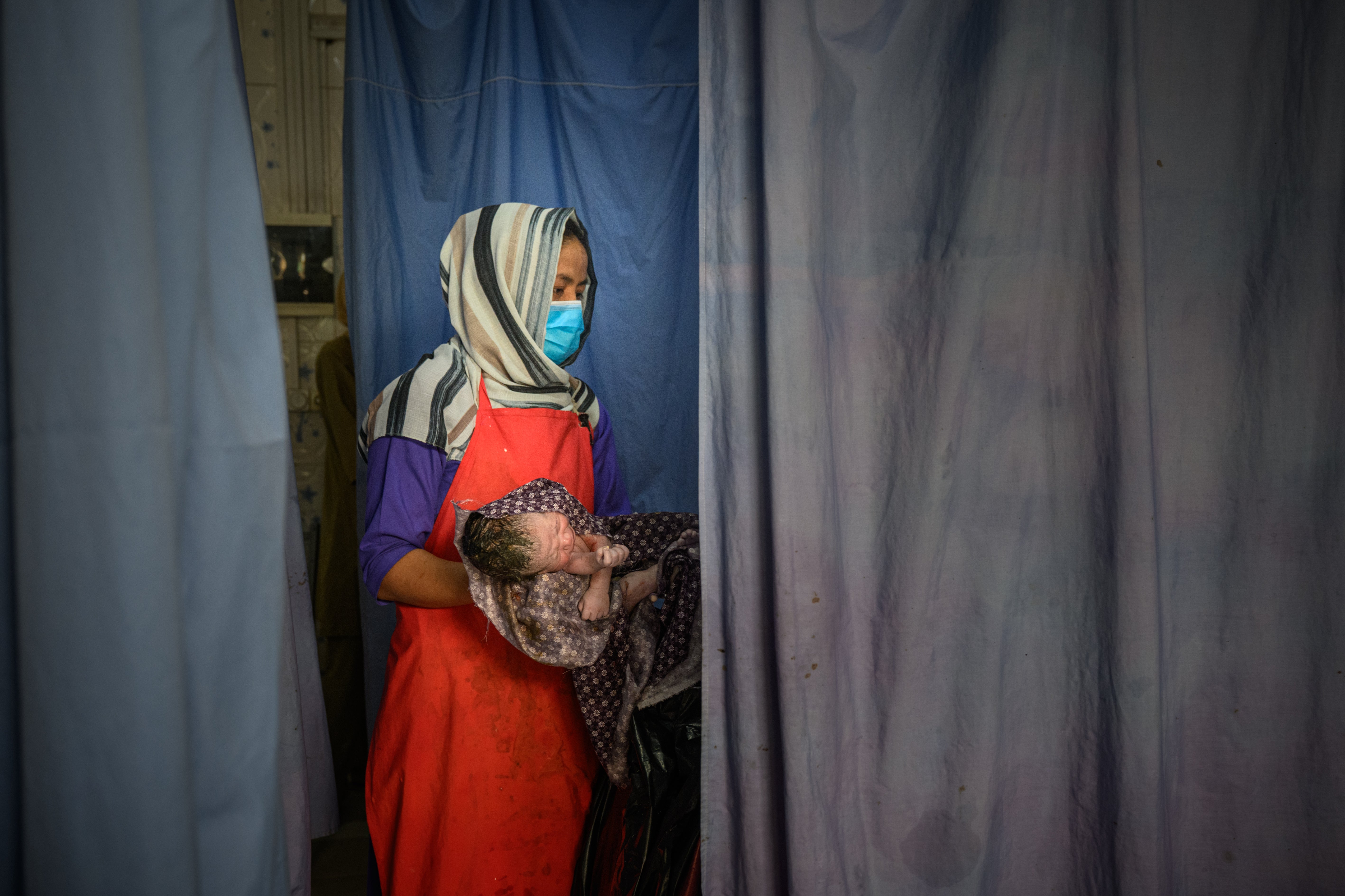 Midwife holds a newborn after a delivery at the provincial hospital's maternity unit in Ghazni