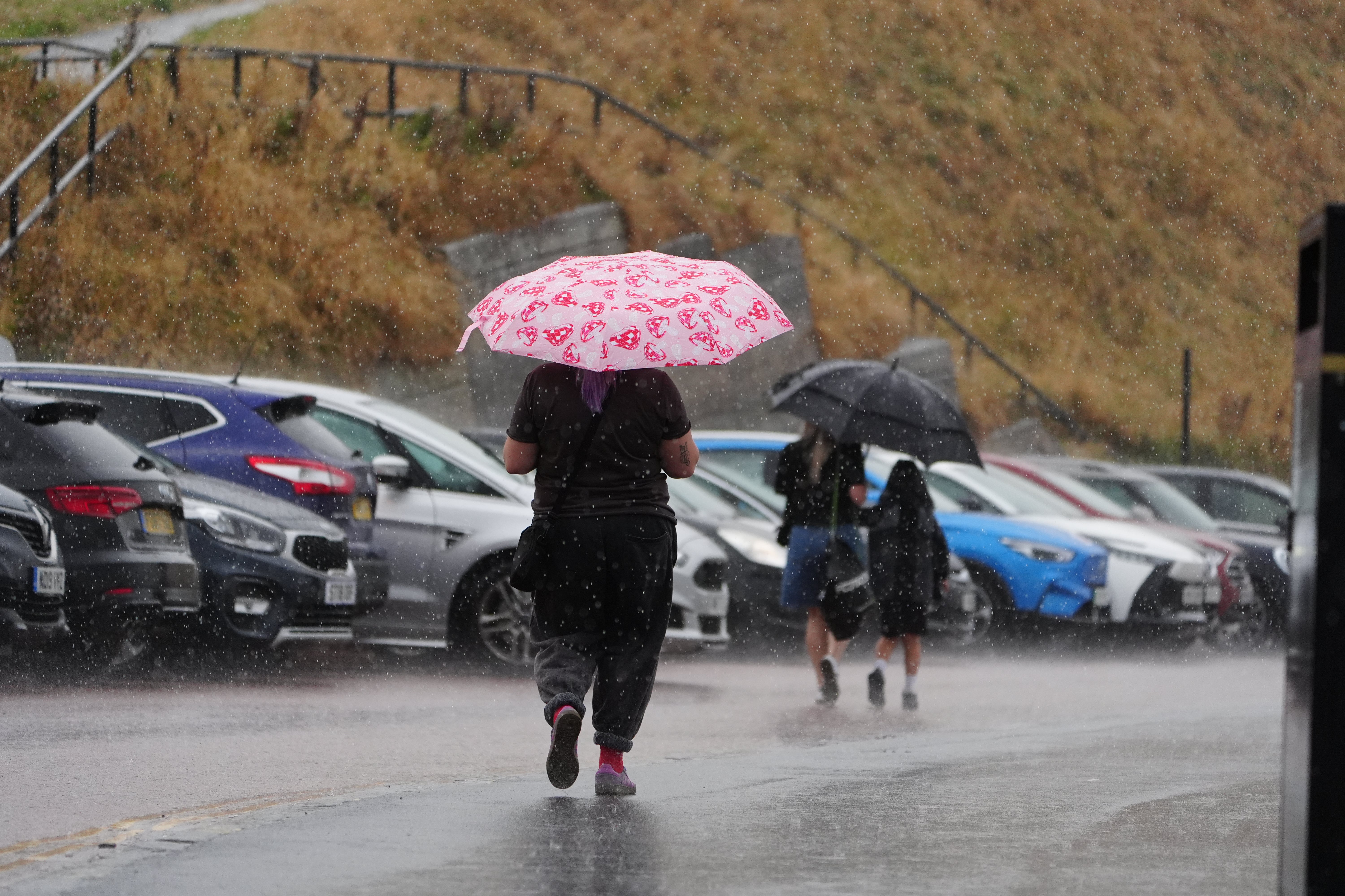 Beachgoers shelter from the rain under umbrellas in Tynemouth (Owen Humphreys/PA) (PA Wire)