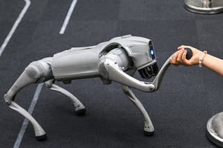 A girl holds the hand of a remote-controlled robot by Unitree Robotics while visiting the Unitree Robotics Embodied Intelligence Experience Center in the Jing' an district in Shanghai