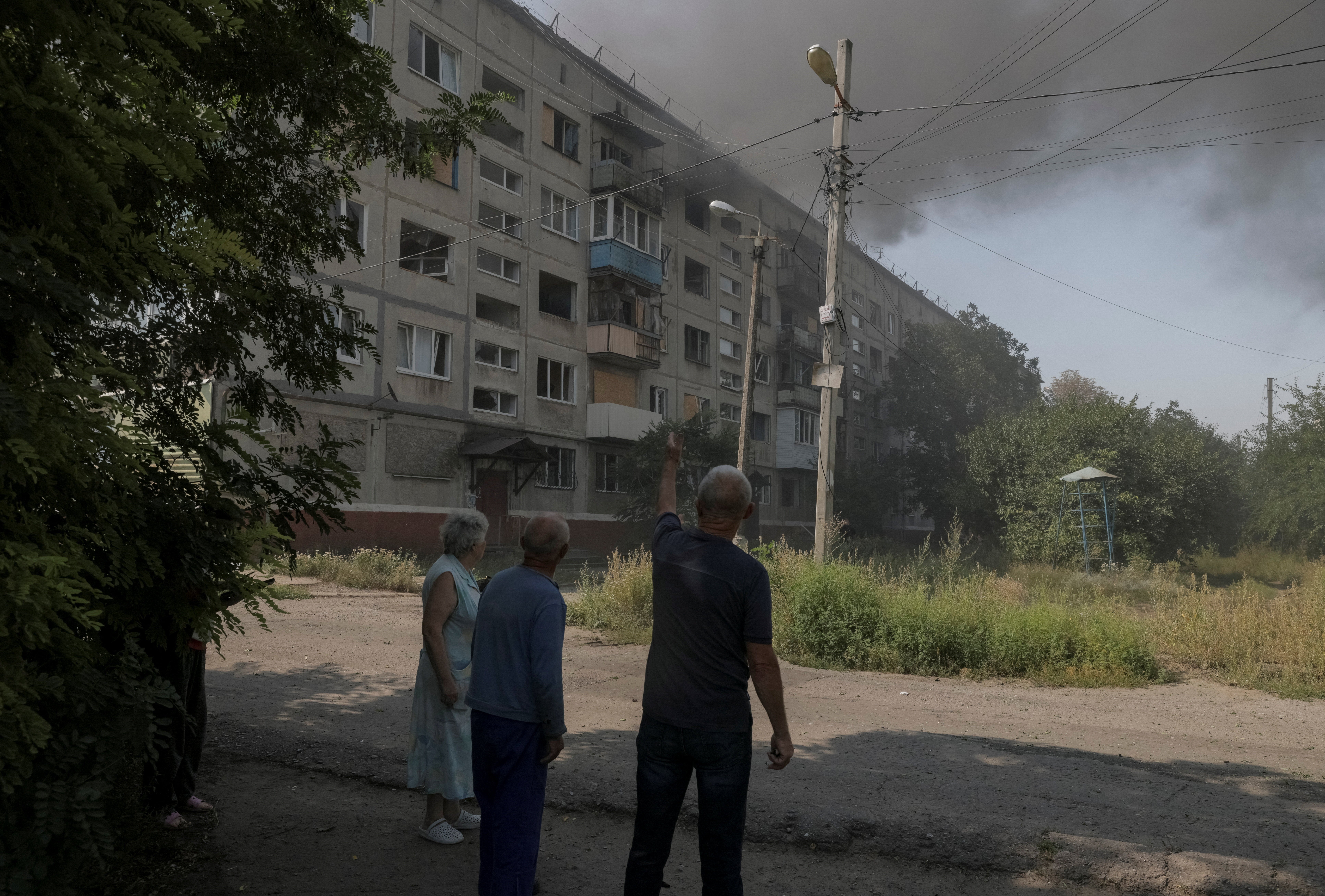 Residents stand at the site of an apartment building hit by a Russian military strike in Donetsk (Reuters)