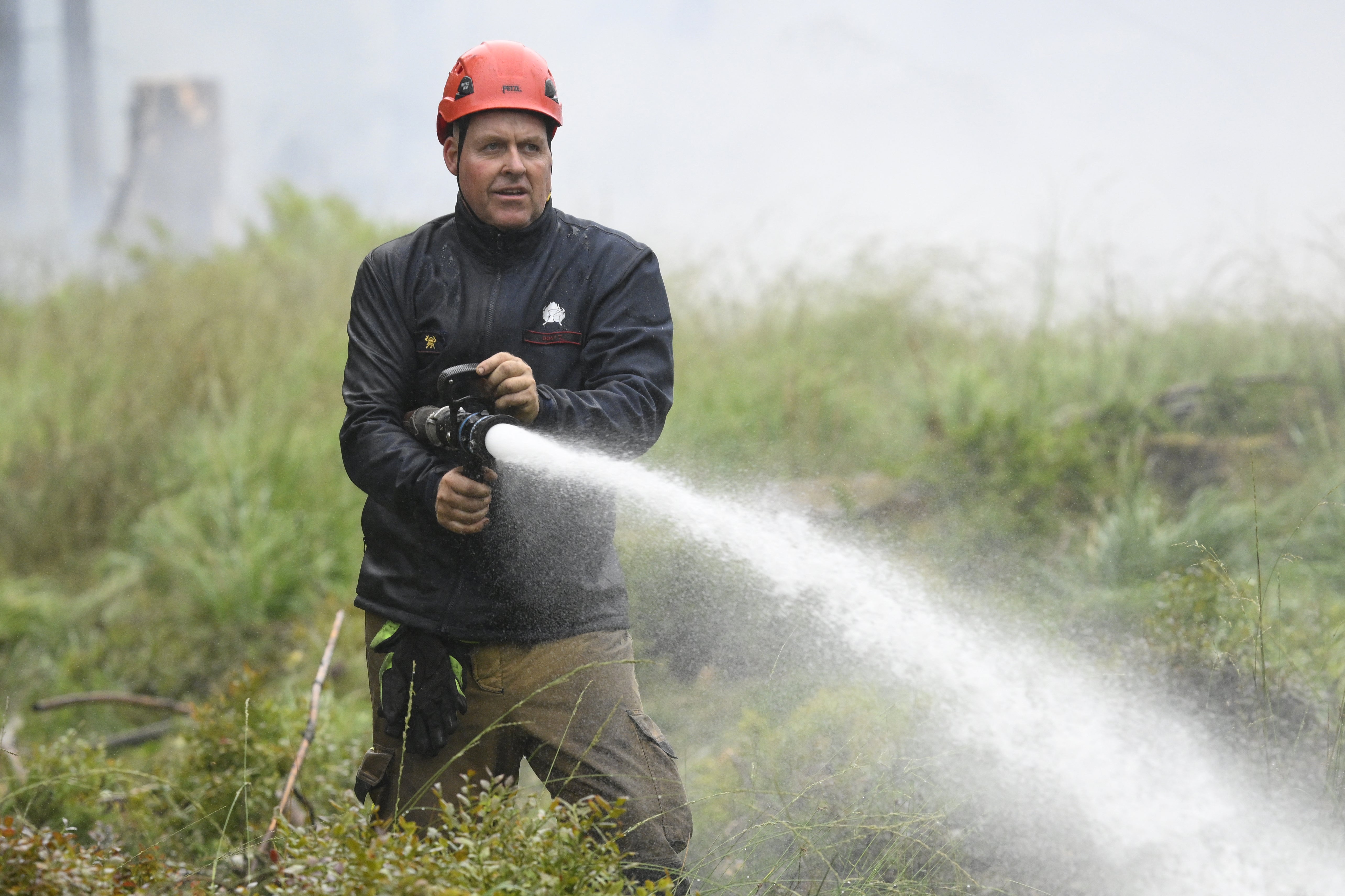 A firefighter sprays water from a hose during operations against a wildfire at the Hautes Fagnes (High Fens) nature reserve near Baelen