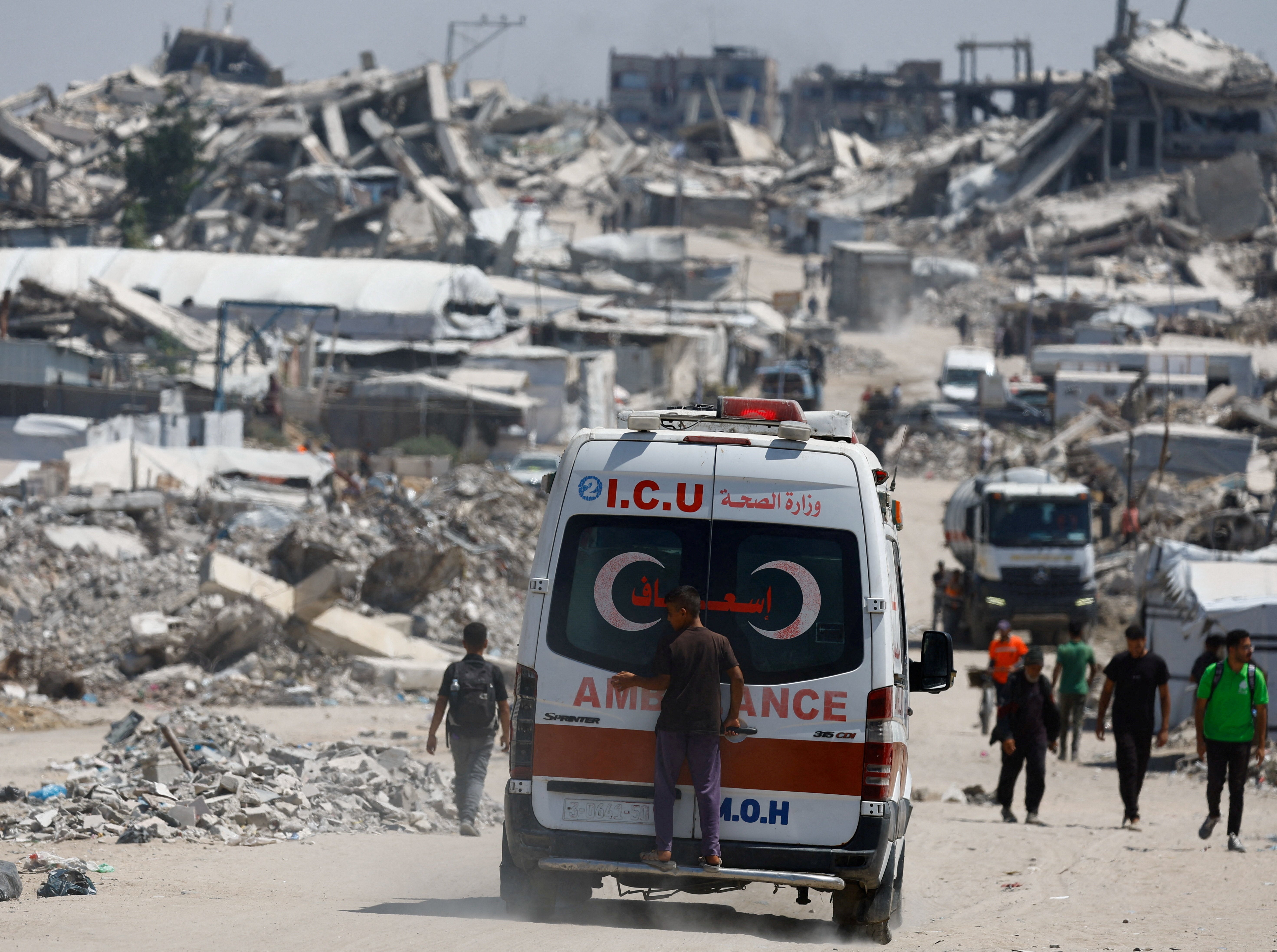 A person stands on the back of an ambulance at a site destroyed during the Israeli offensive, in Beit Lahiya