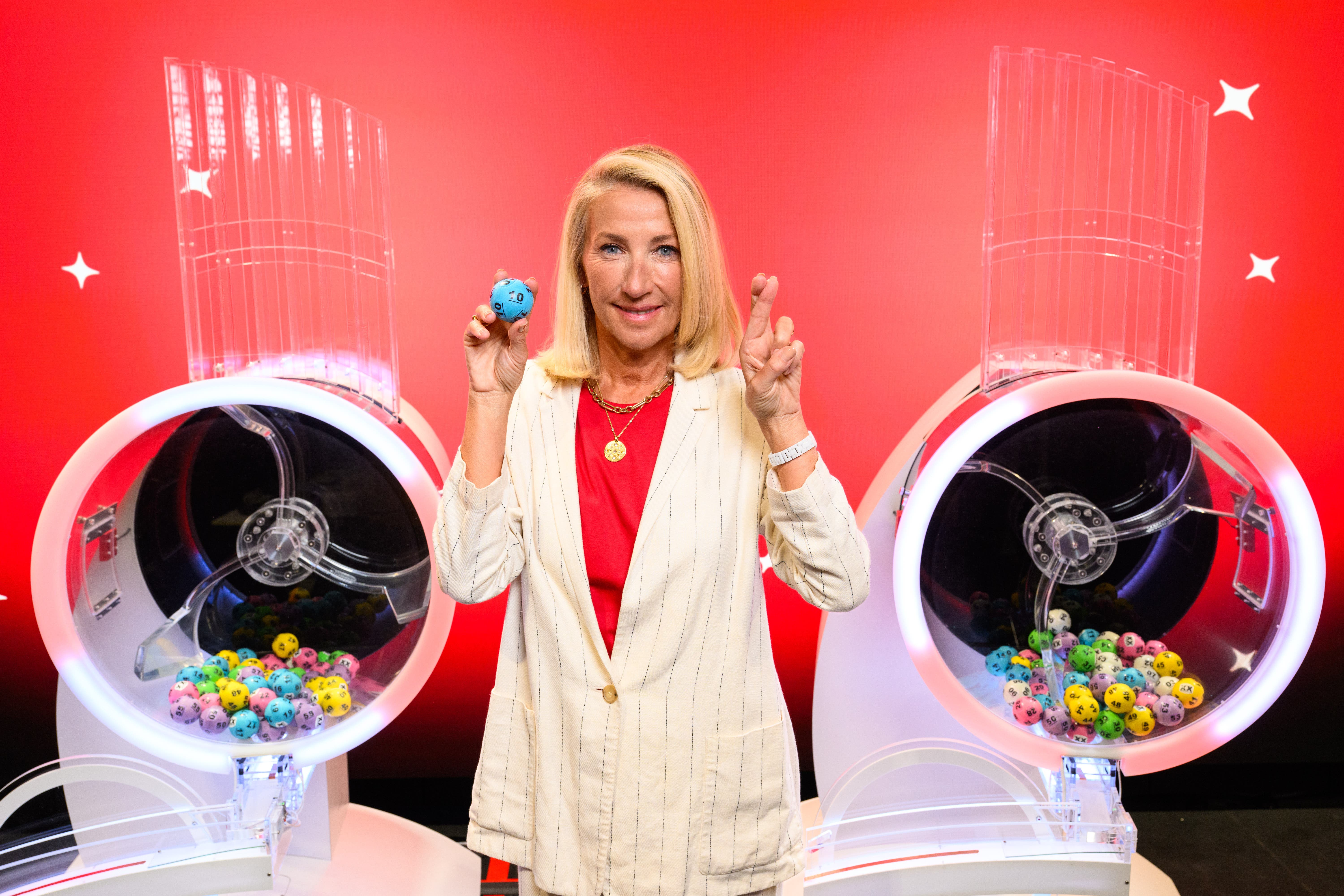 Andria Vidler crossing her fingers while standing next to do Lottery games machines