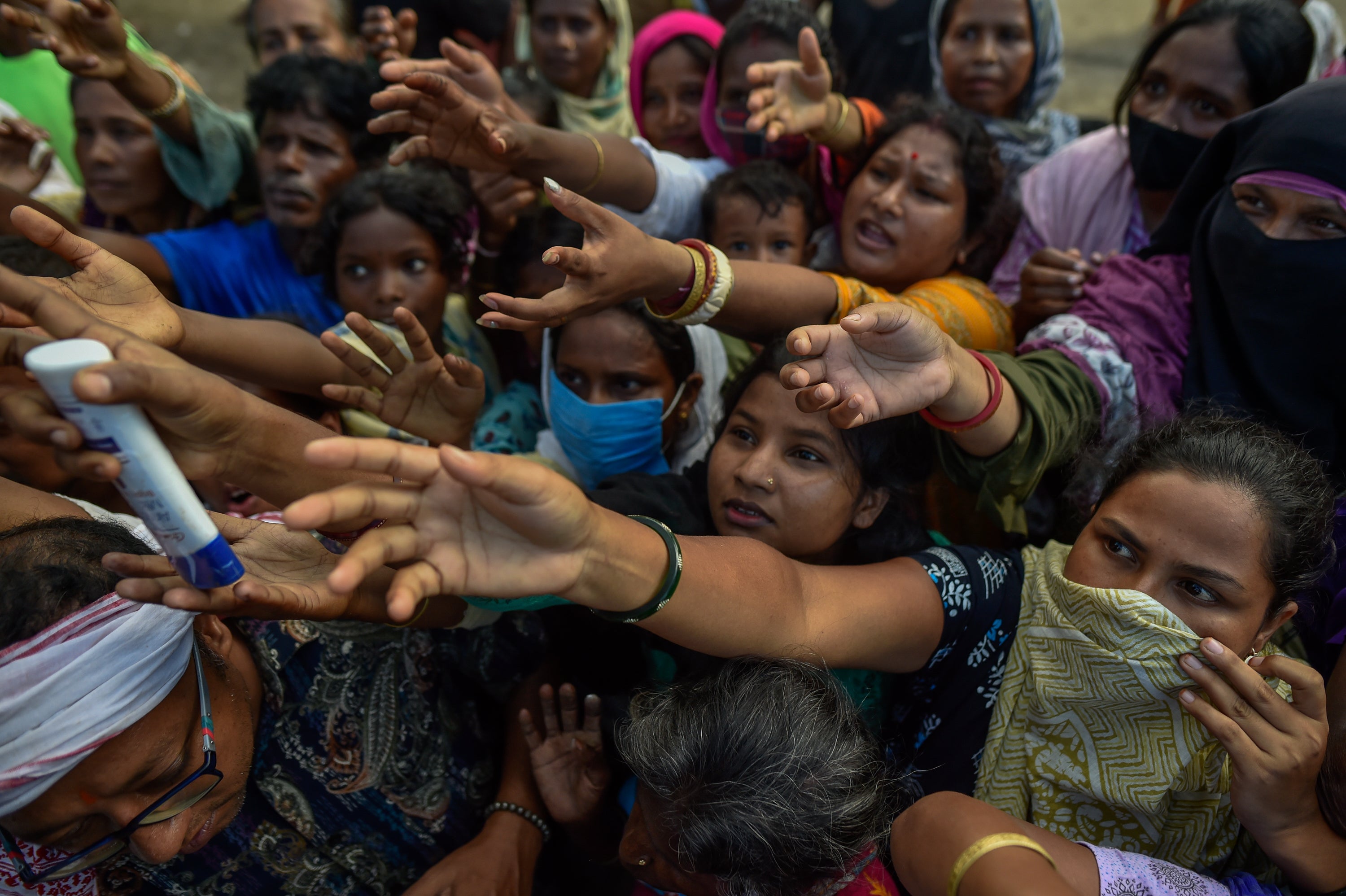 Flood affected residents reach out to receive relief supplies during a distribution at a temporary relief camp on August 05, 2026 in Sivasagar, Assam, India (Getty)