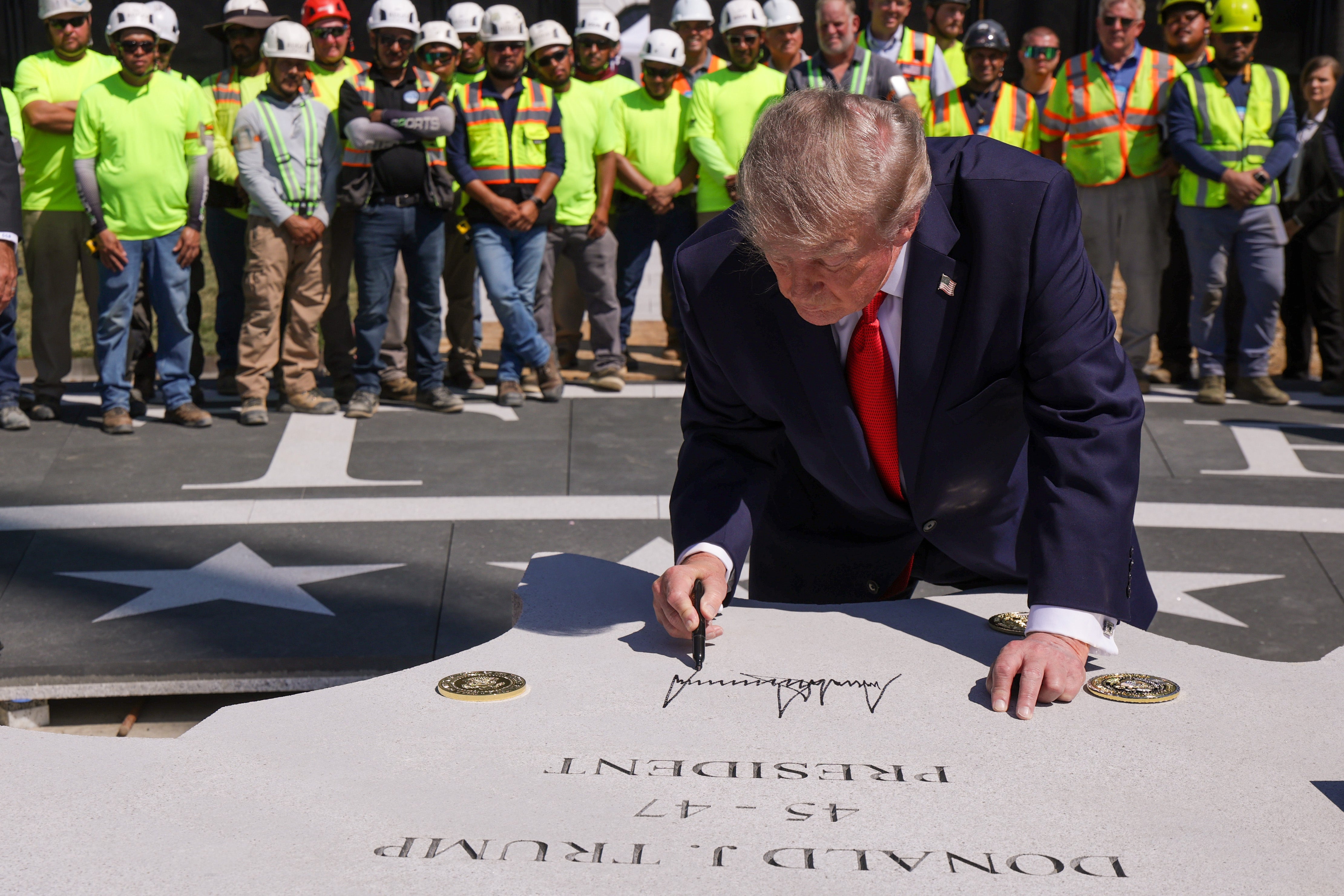 President Donald Trump signs a piece of granite that will be part of the new helipad on the South Lawn of the White House on Wednesday (Getty)